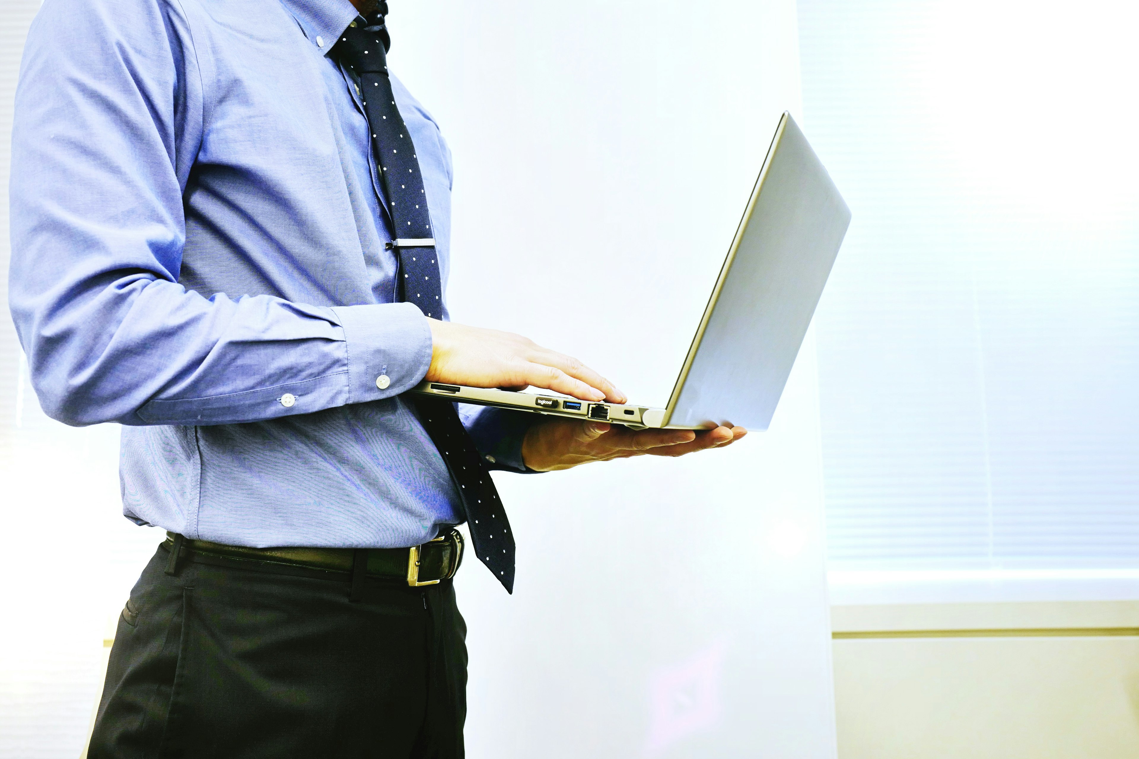 A businessman in a dress shirt and tie holding a laptop