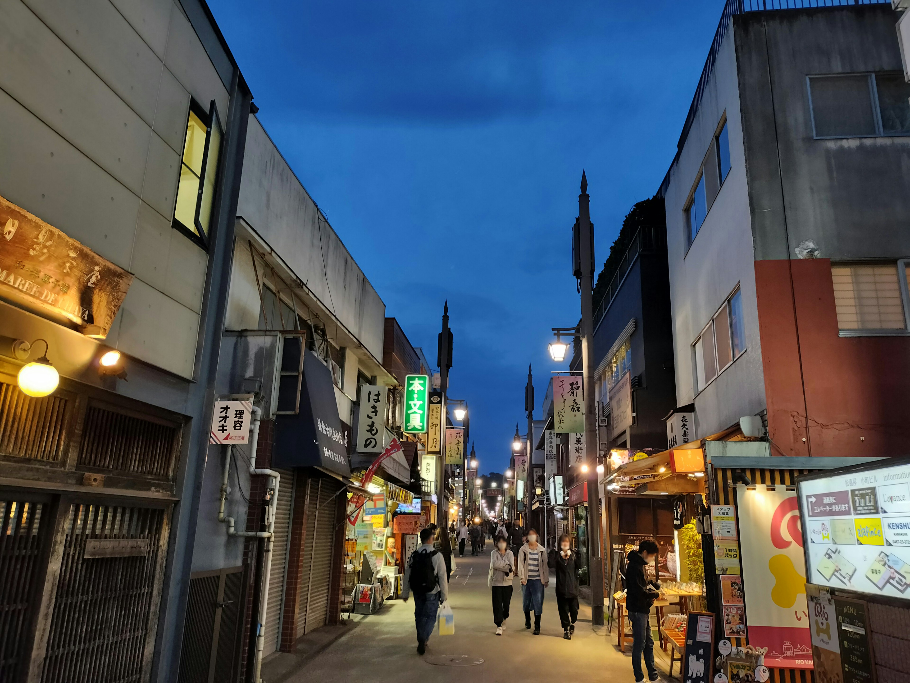 A street scene with people walking and shops lining the road at night