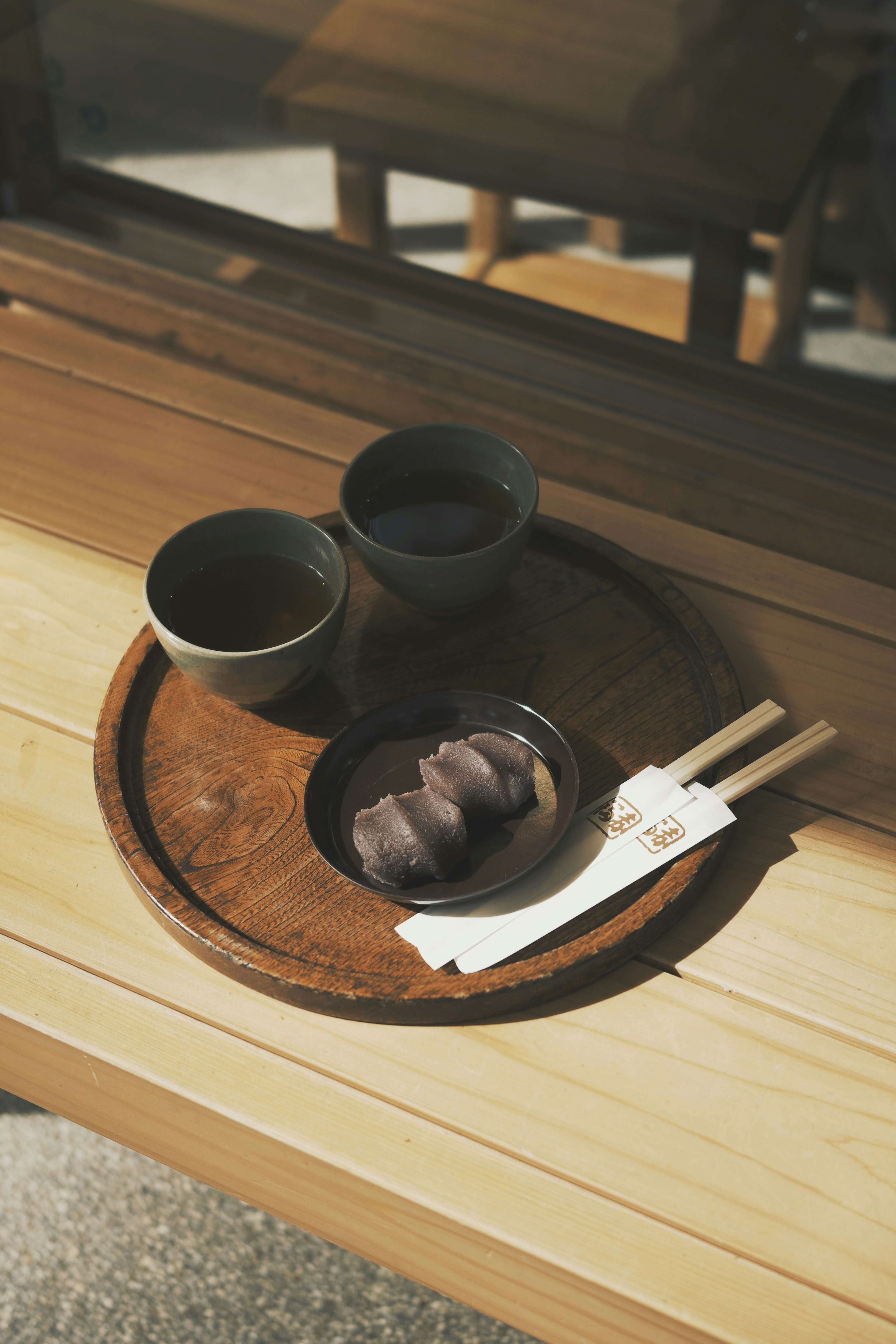 木のトレイに置かれた二つの茶碗と和菓子の皿