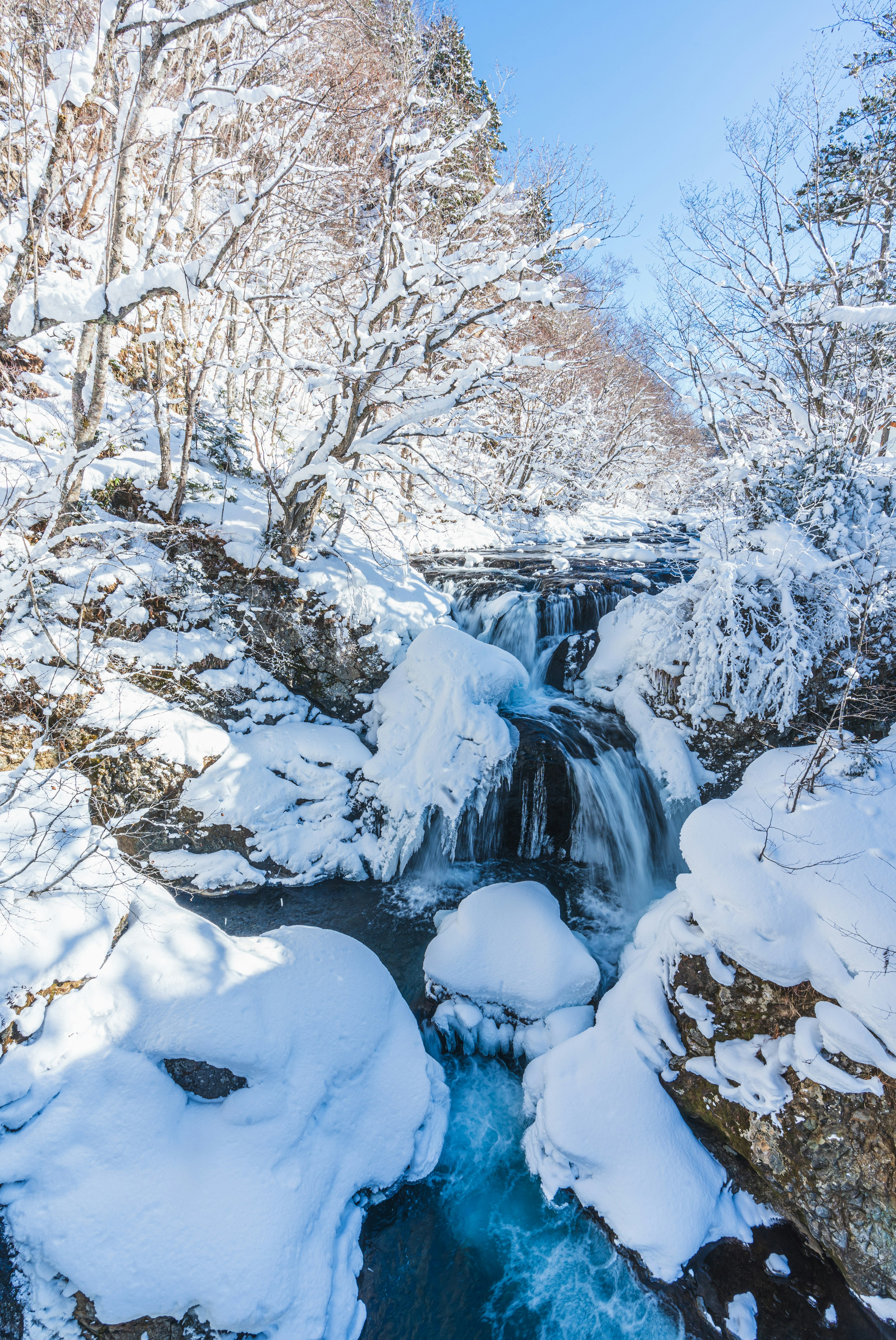 Snow-covered waterfall with flowing blue water