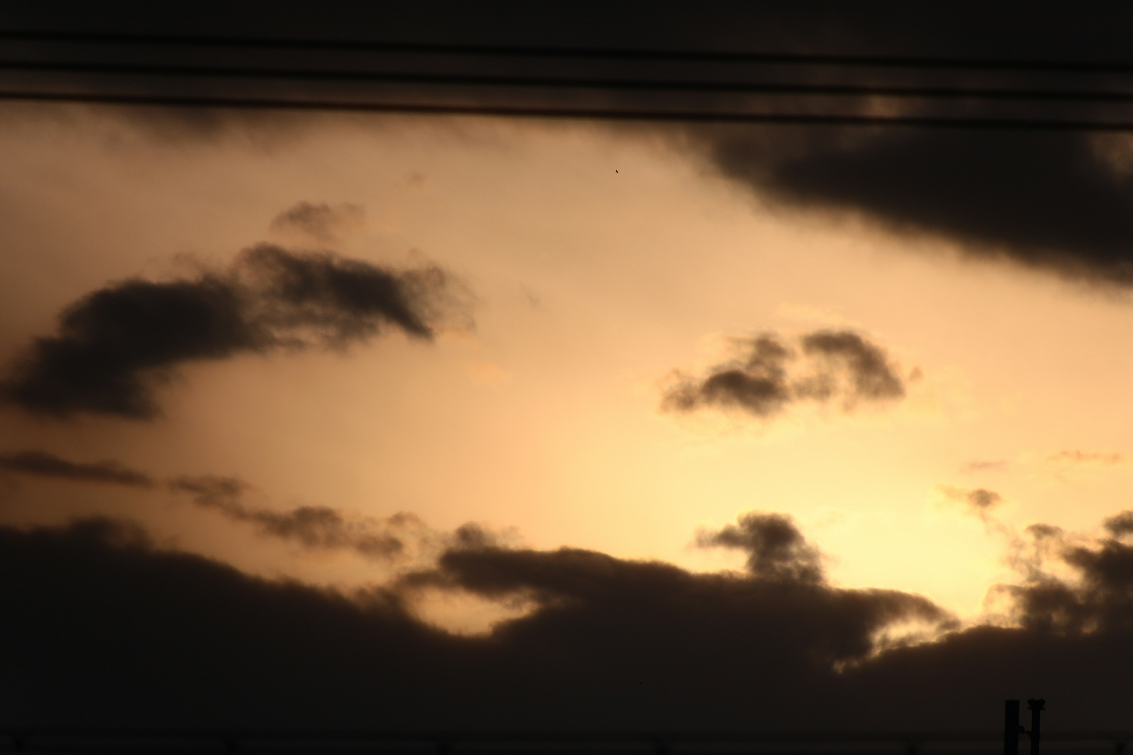 Silhouette of dark clouds against an orange sunset sky