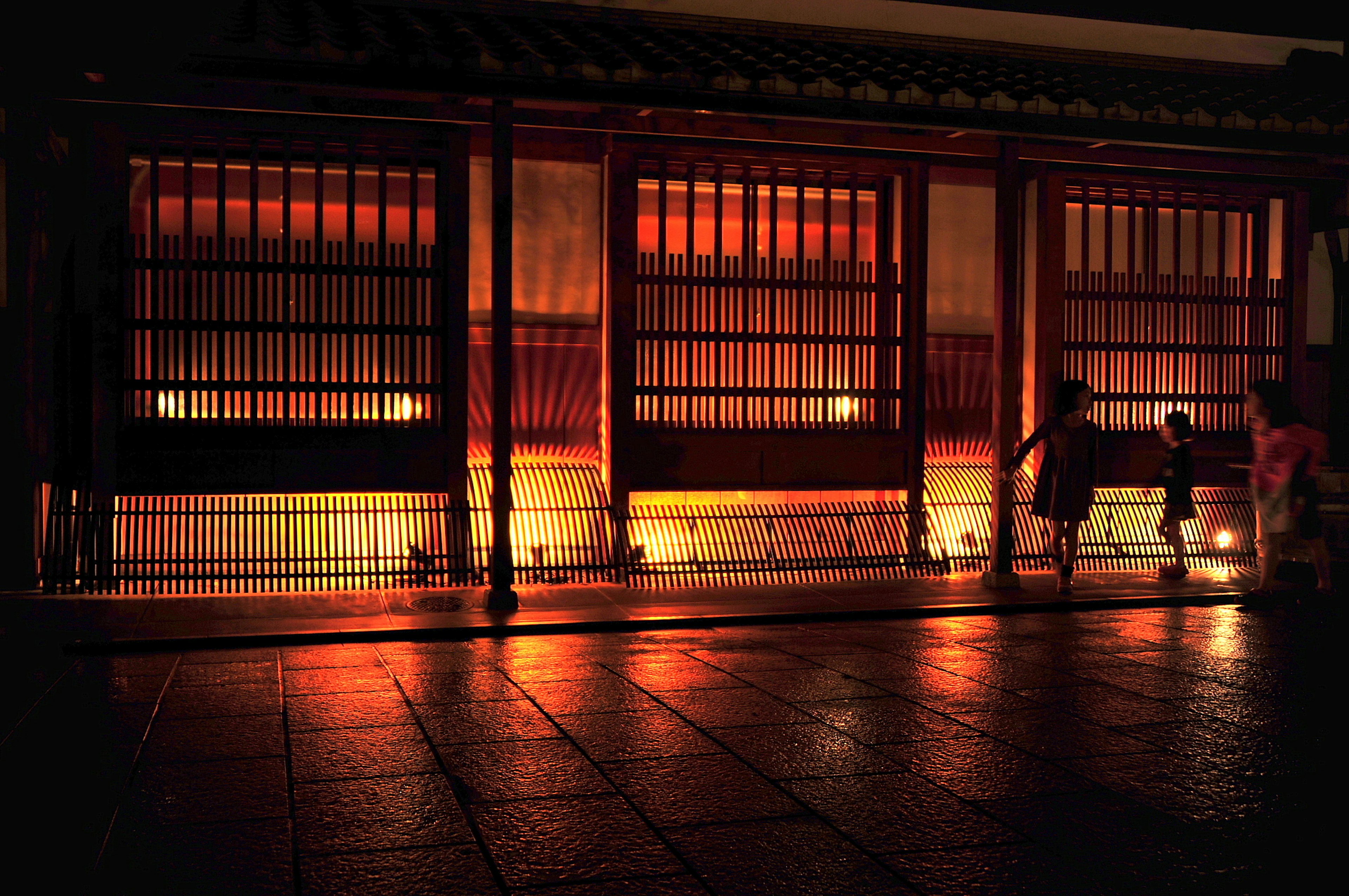 Extérieur d'un bâtiment traditionnel illuminé la nuit avec des reflets au sol