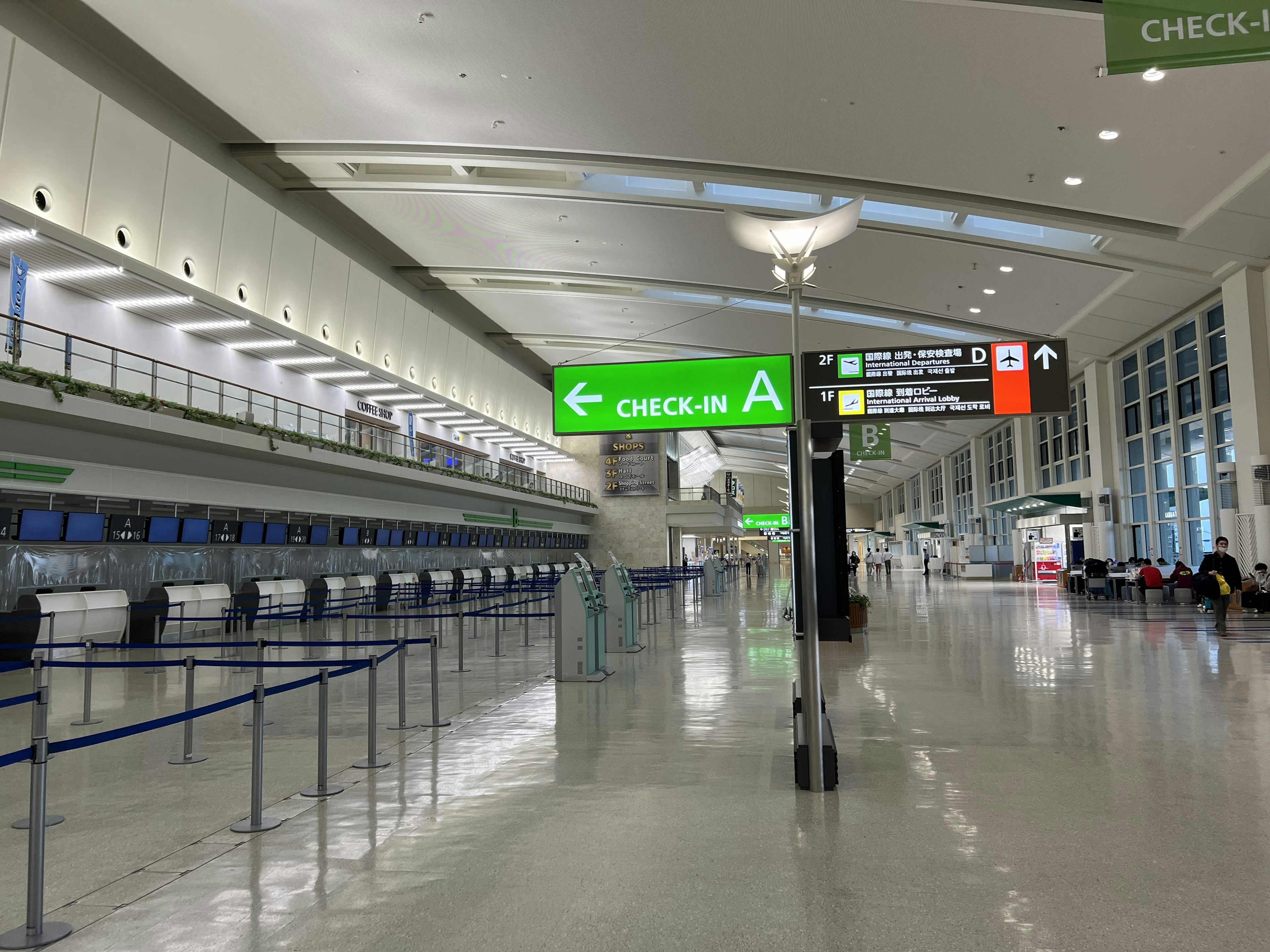 Amplio interior de aeropuerto con área de check-in y señalización direccional