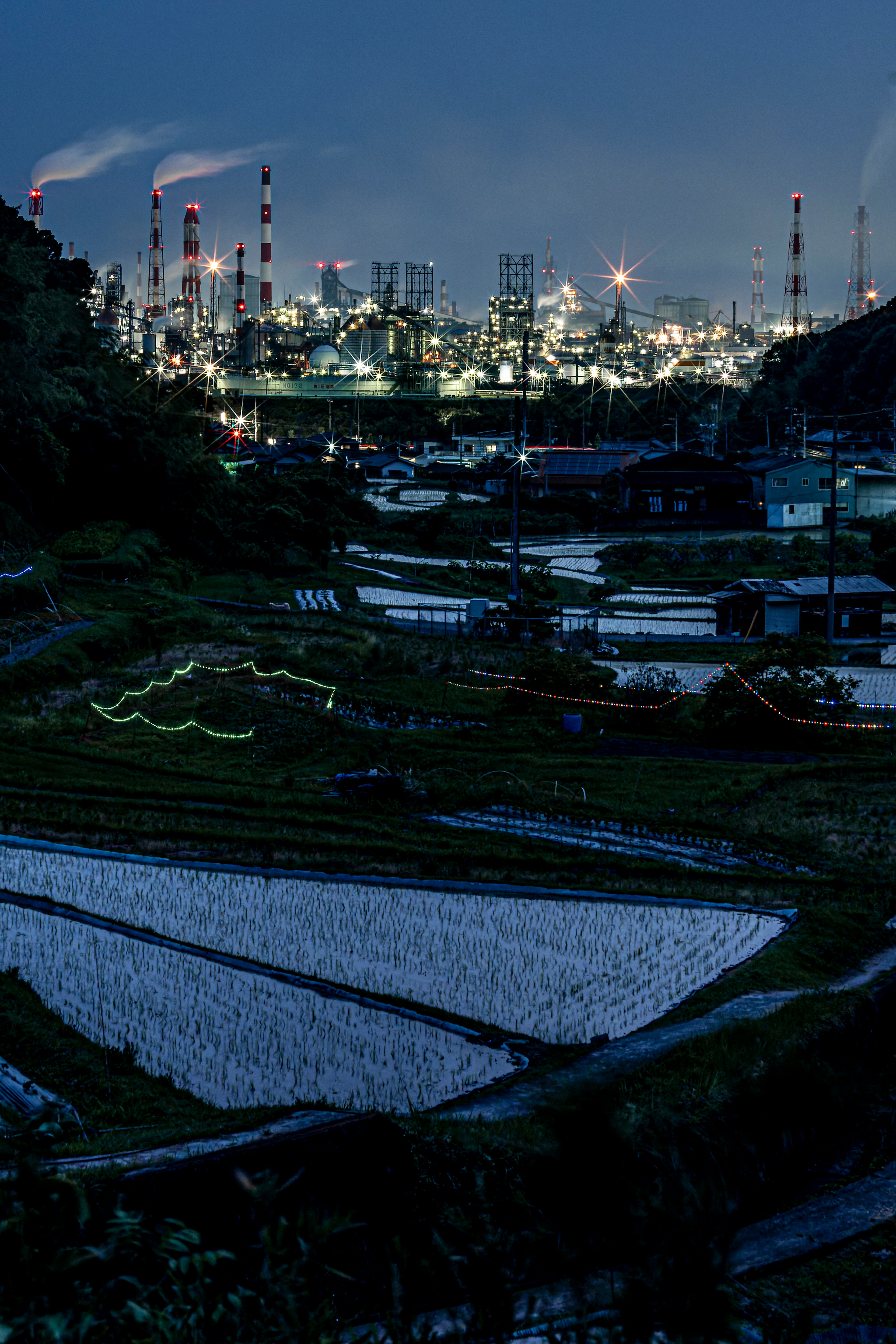 夜の工業地帯と田んぼの風景 工場の煙突が立ち並ぶ