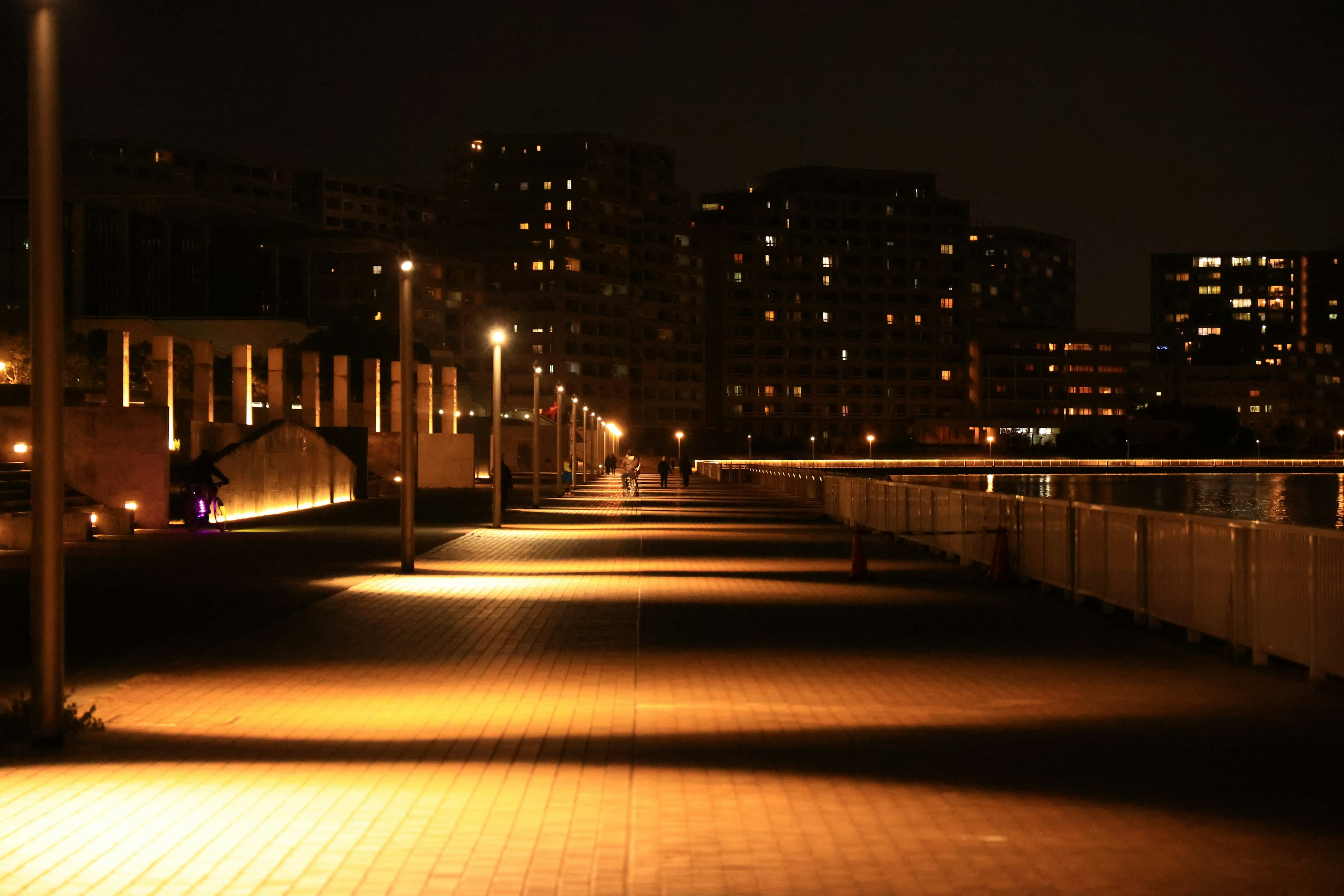 Städtischer Gehweg bei Nacht beleuchtet von Straßenlaternen