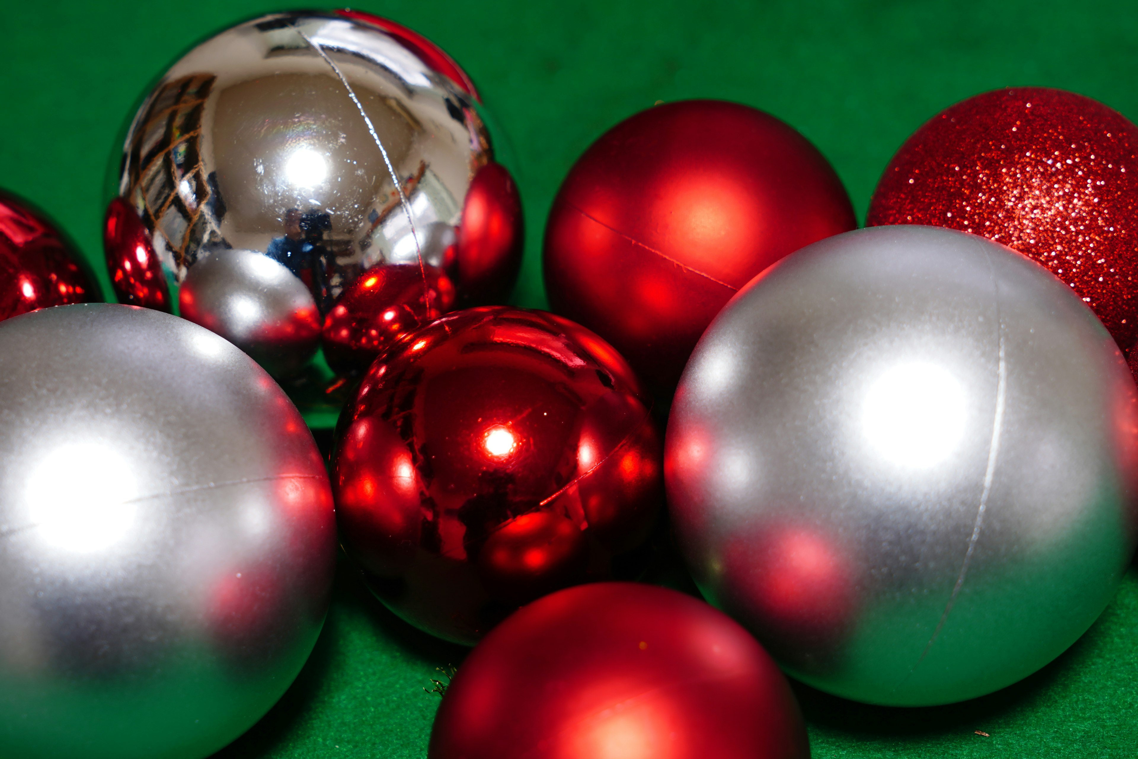 Red and silver Christmas ornaments arranged on a green background