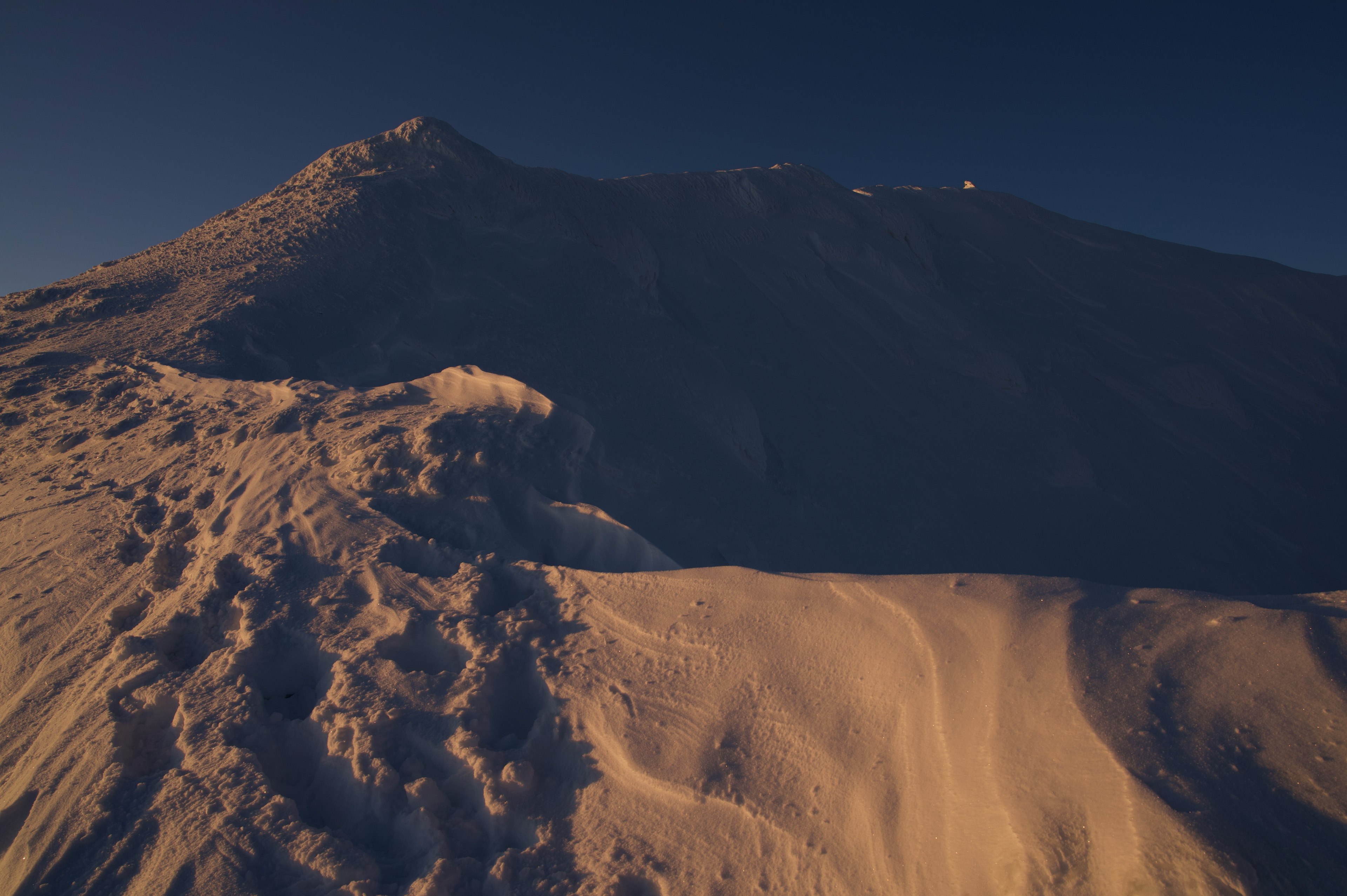 Paisaje montañoso cubierto de nieve con cielo oscuro