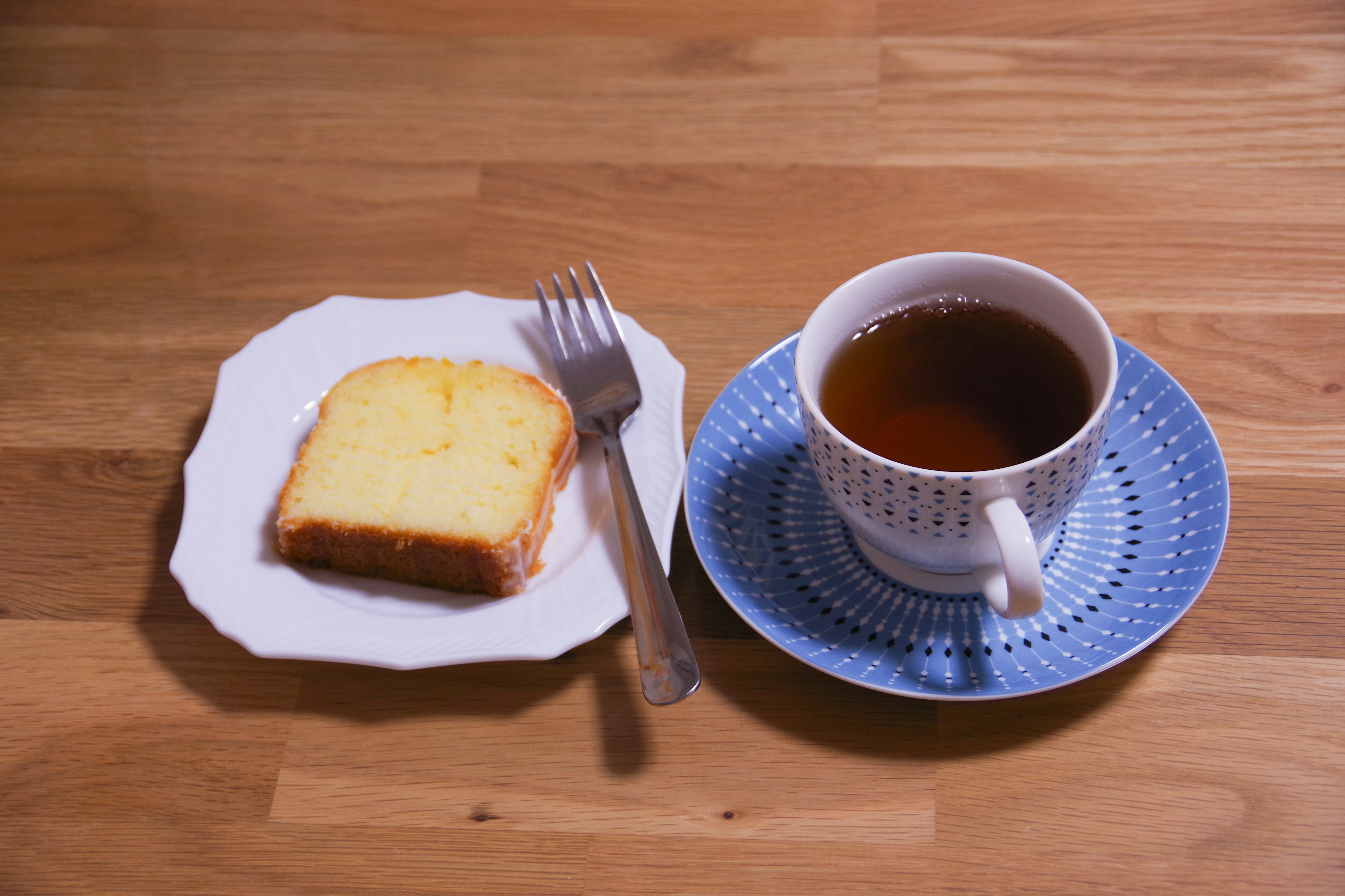 Eine Tasse Tee und ein Stück Kuchen auf einem Holztisch