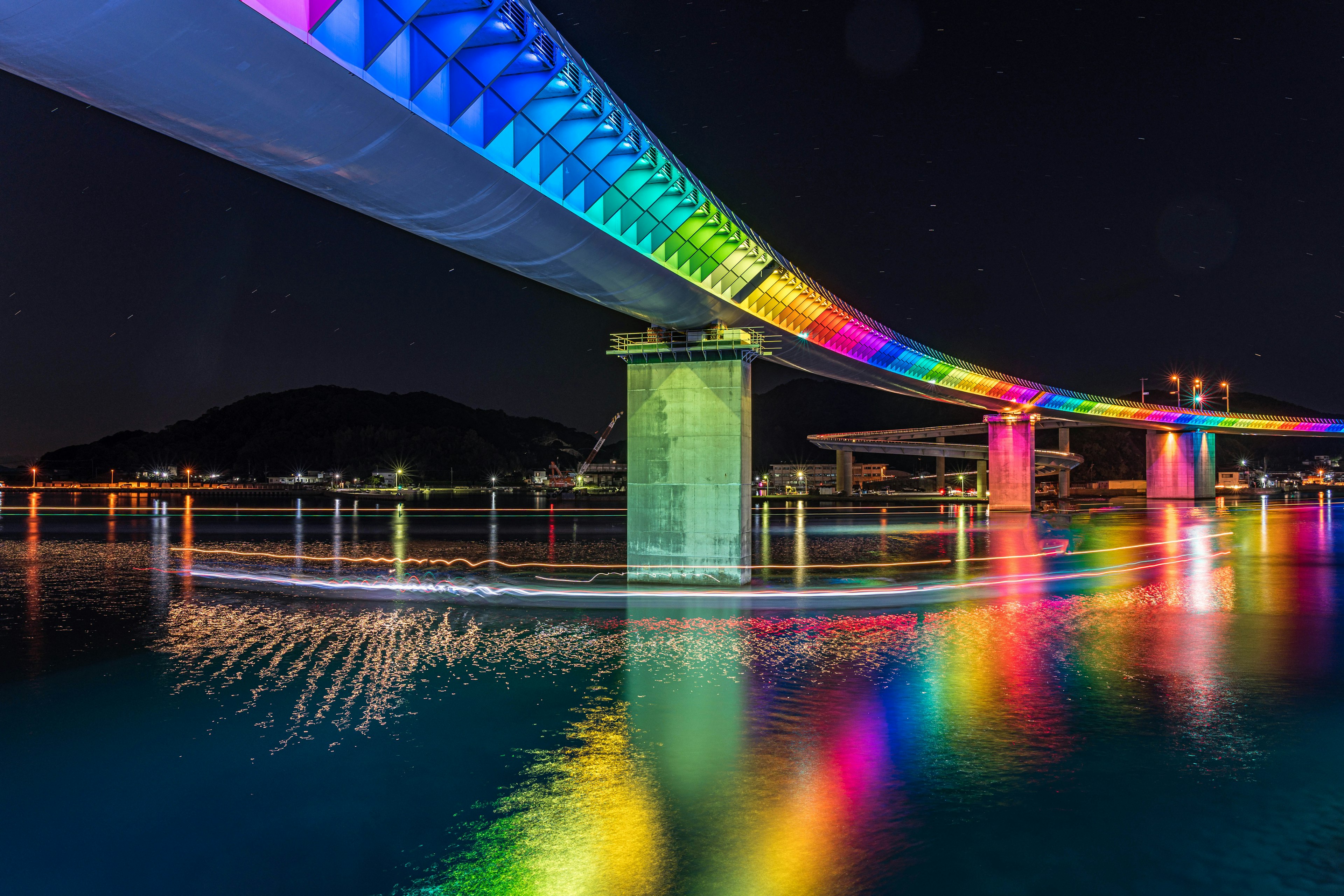 Puente iluminado colorido por la noche con reflejos en el agua