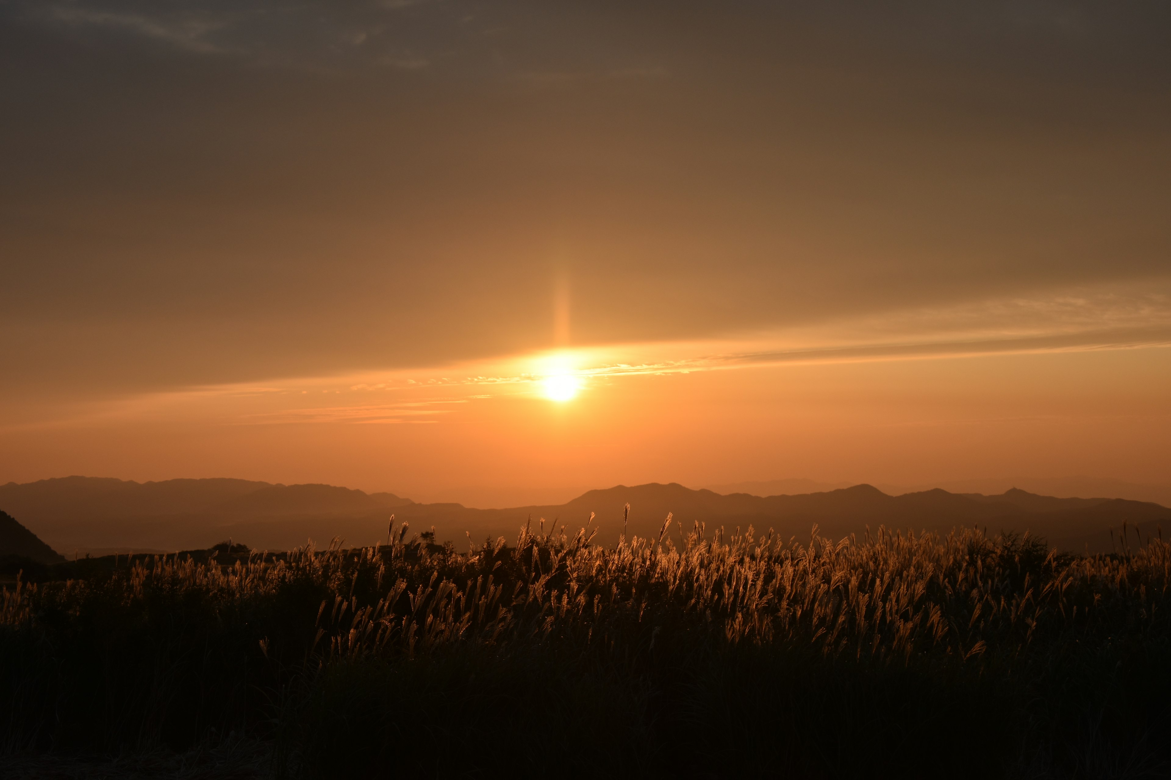 夕日が山々の背後に沈む美しい風景