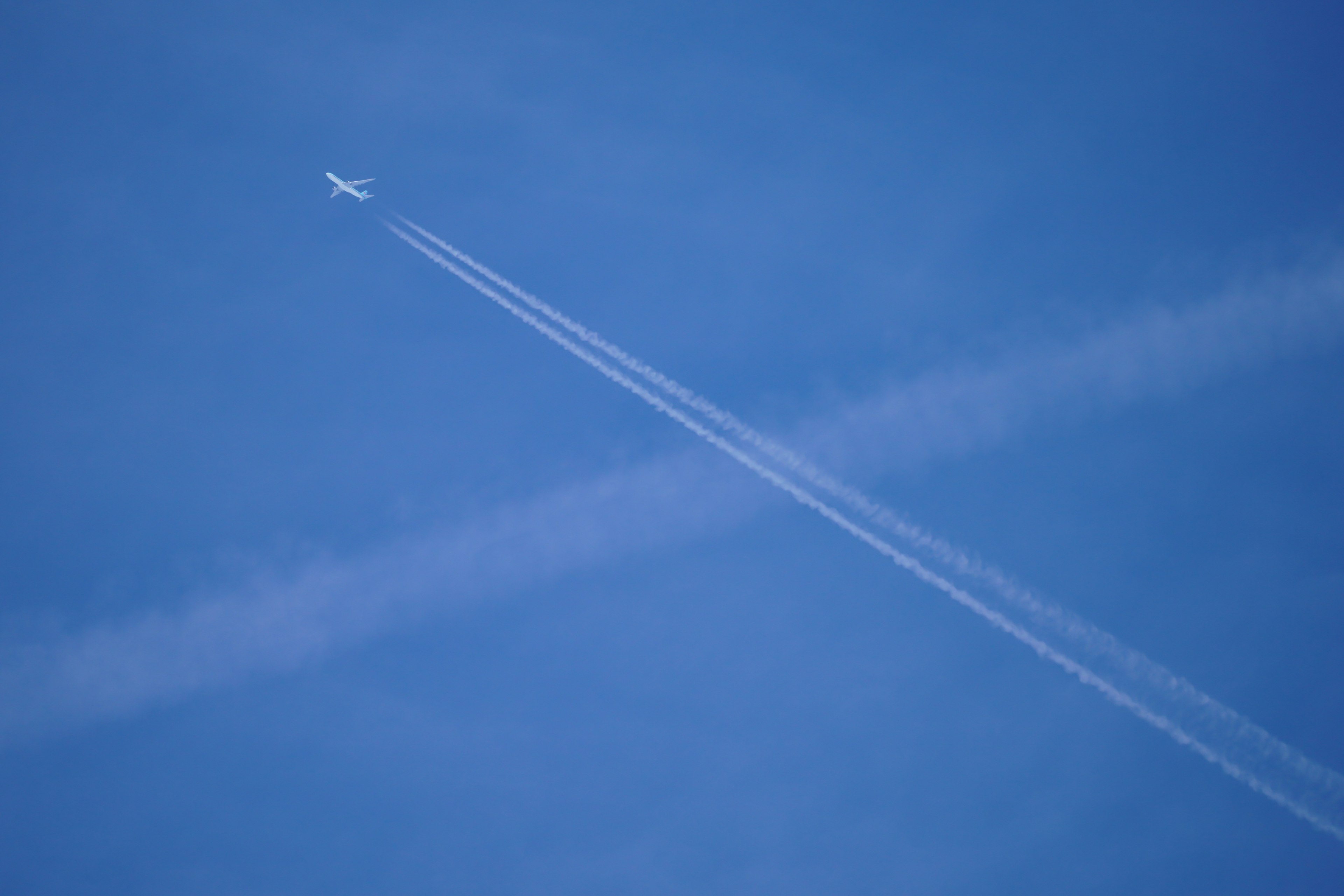 Airplane flying in a clear blue sky with contrails