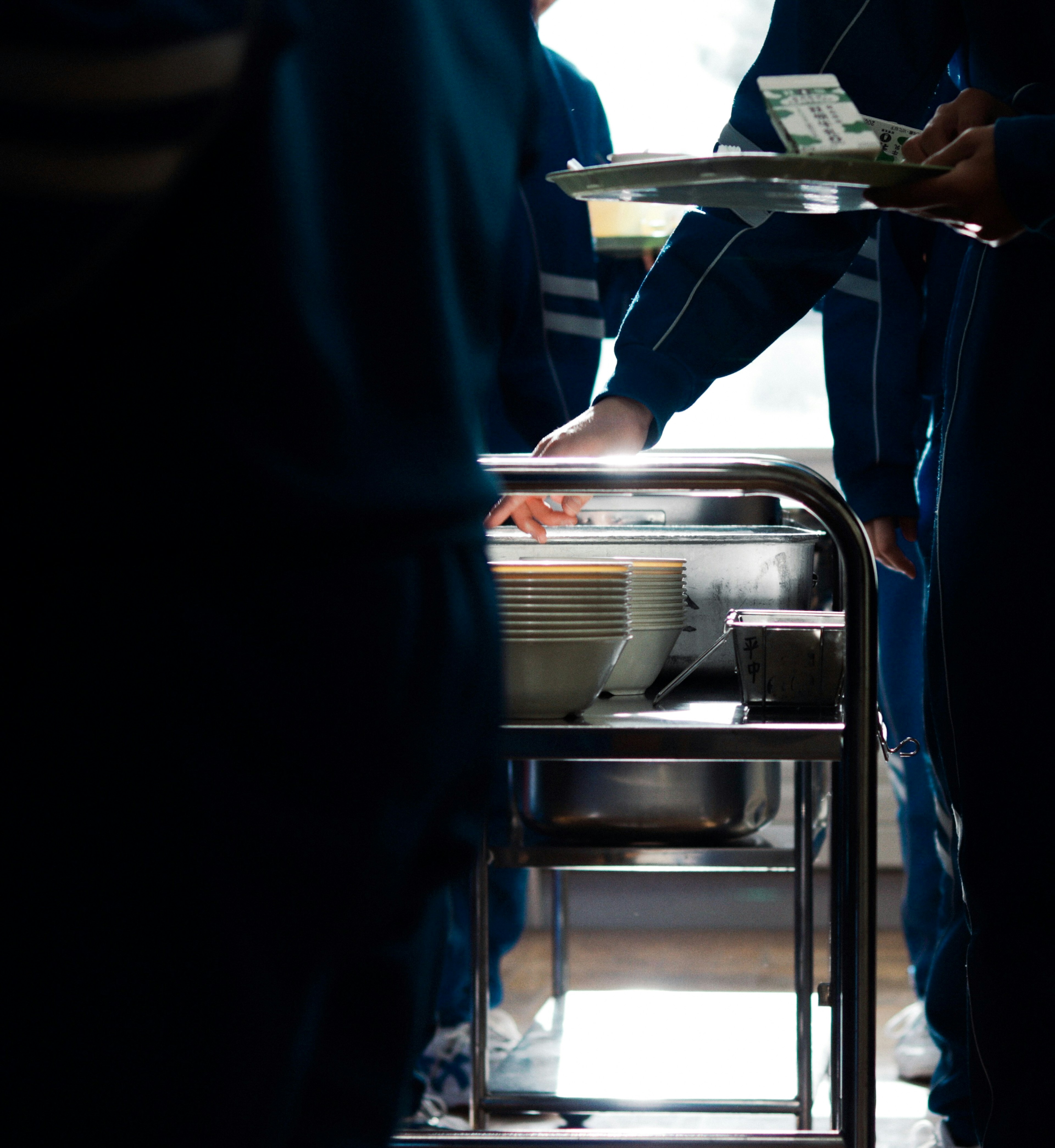 Silhouettes of students serving food in a cafeteria