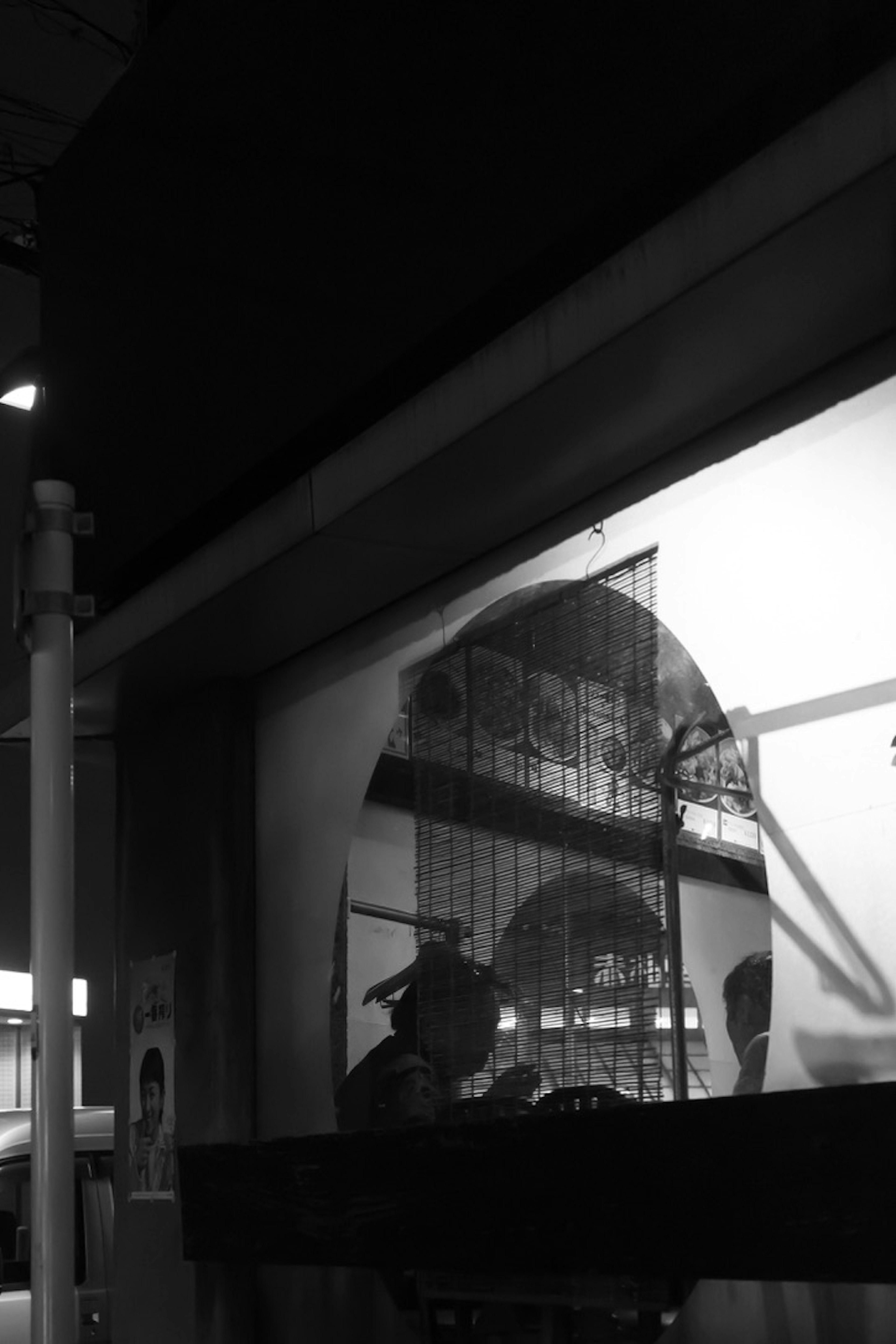 Una persona sentada junto a una ventana en una escena en blanco y negro