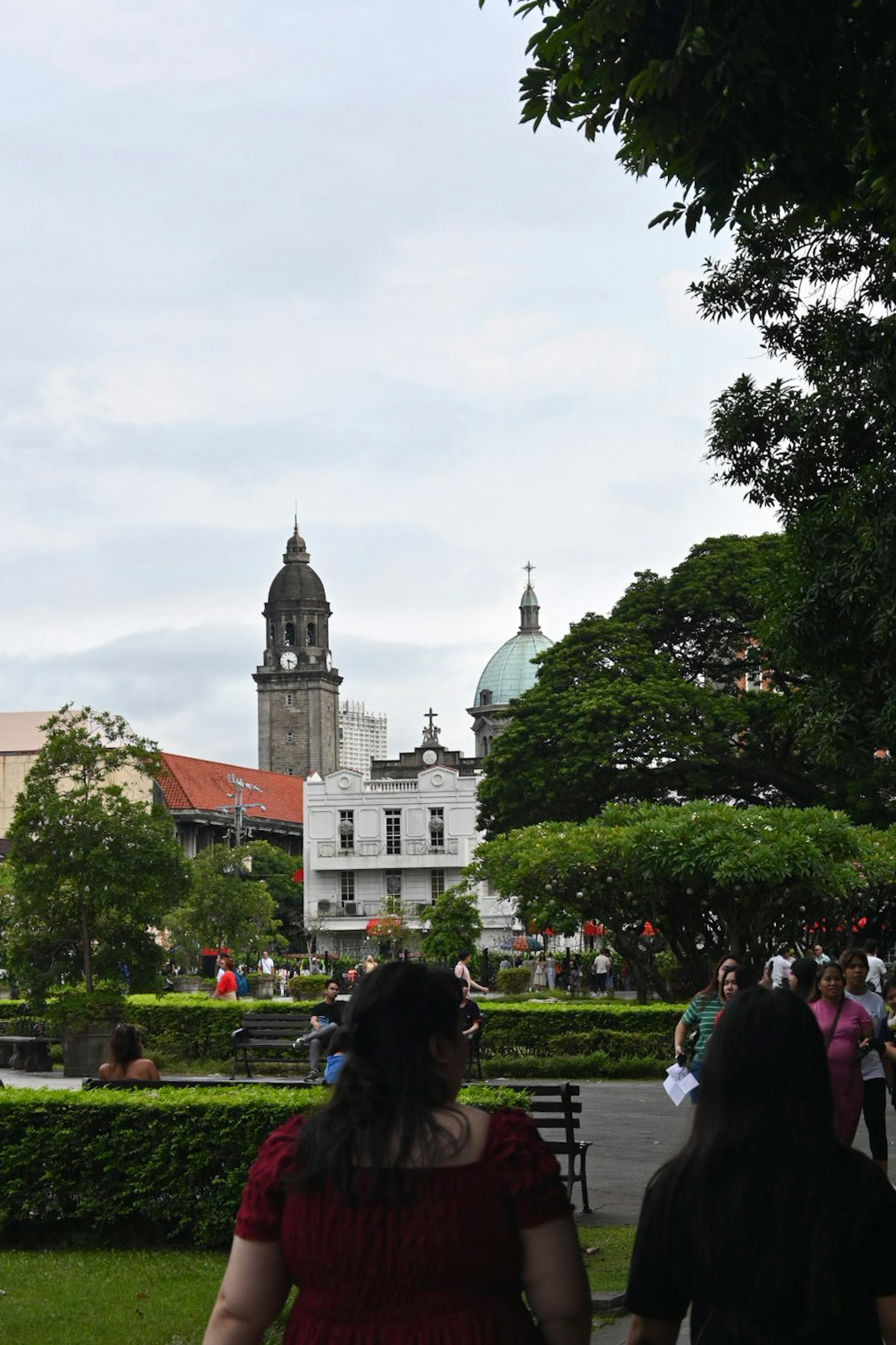 People walking in a park with historical buildings in the background