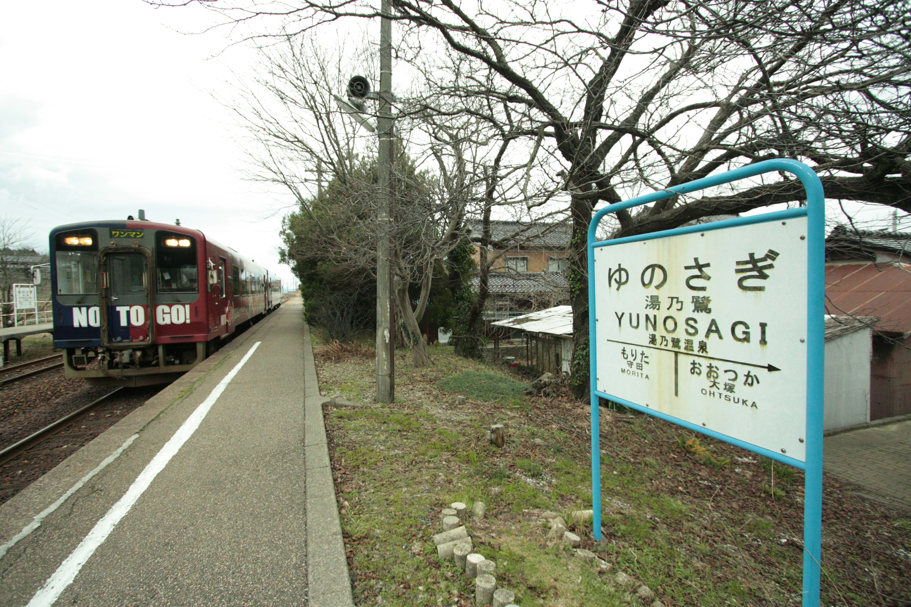 Panneau de la gare Yunosagi avec un train à l'arrêt à proximité