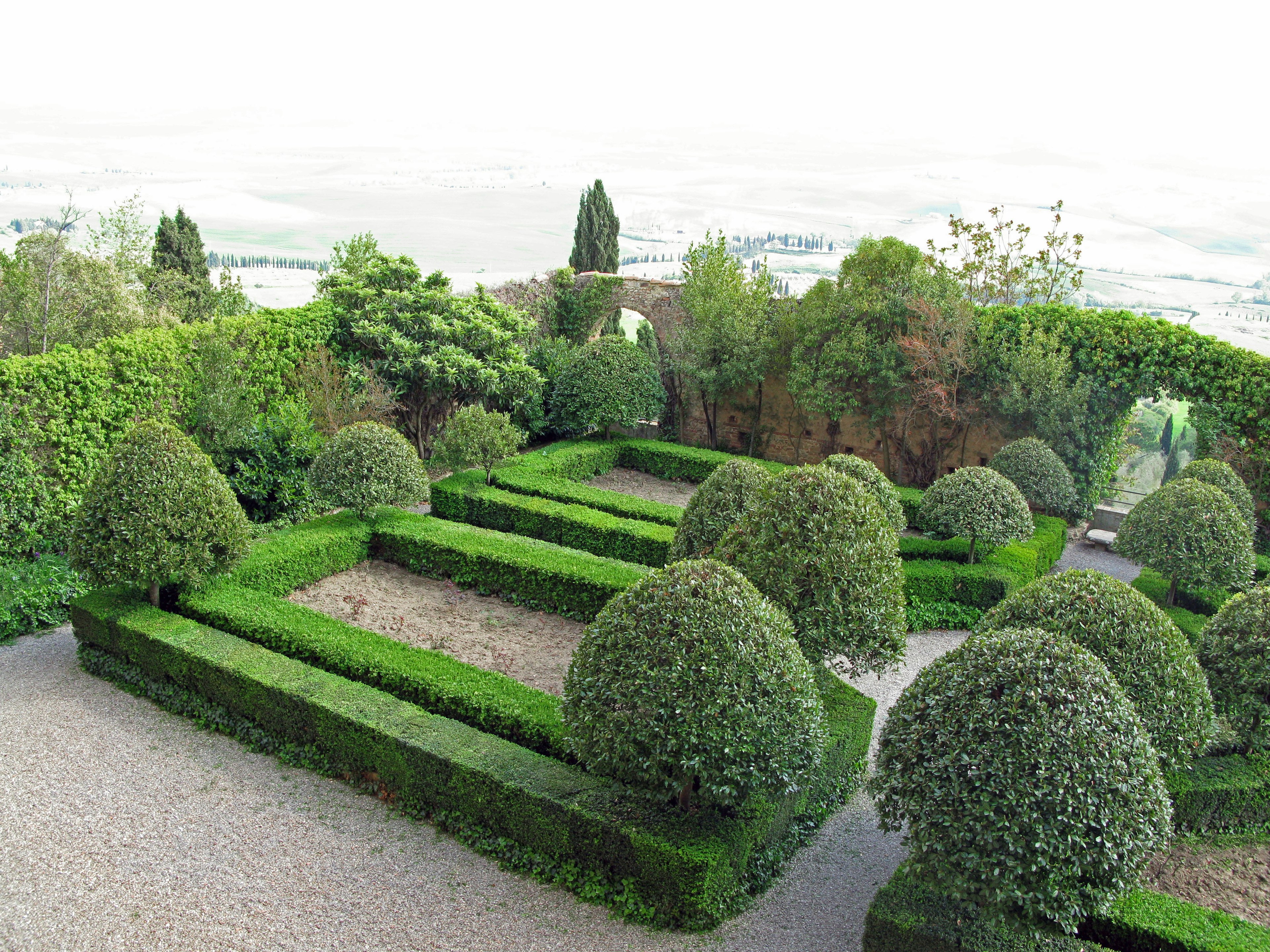 Vue pittoresque d'un beau jardin avec des haies soigneusement taillées et des arbres sphériques surplombant un paysage lointain