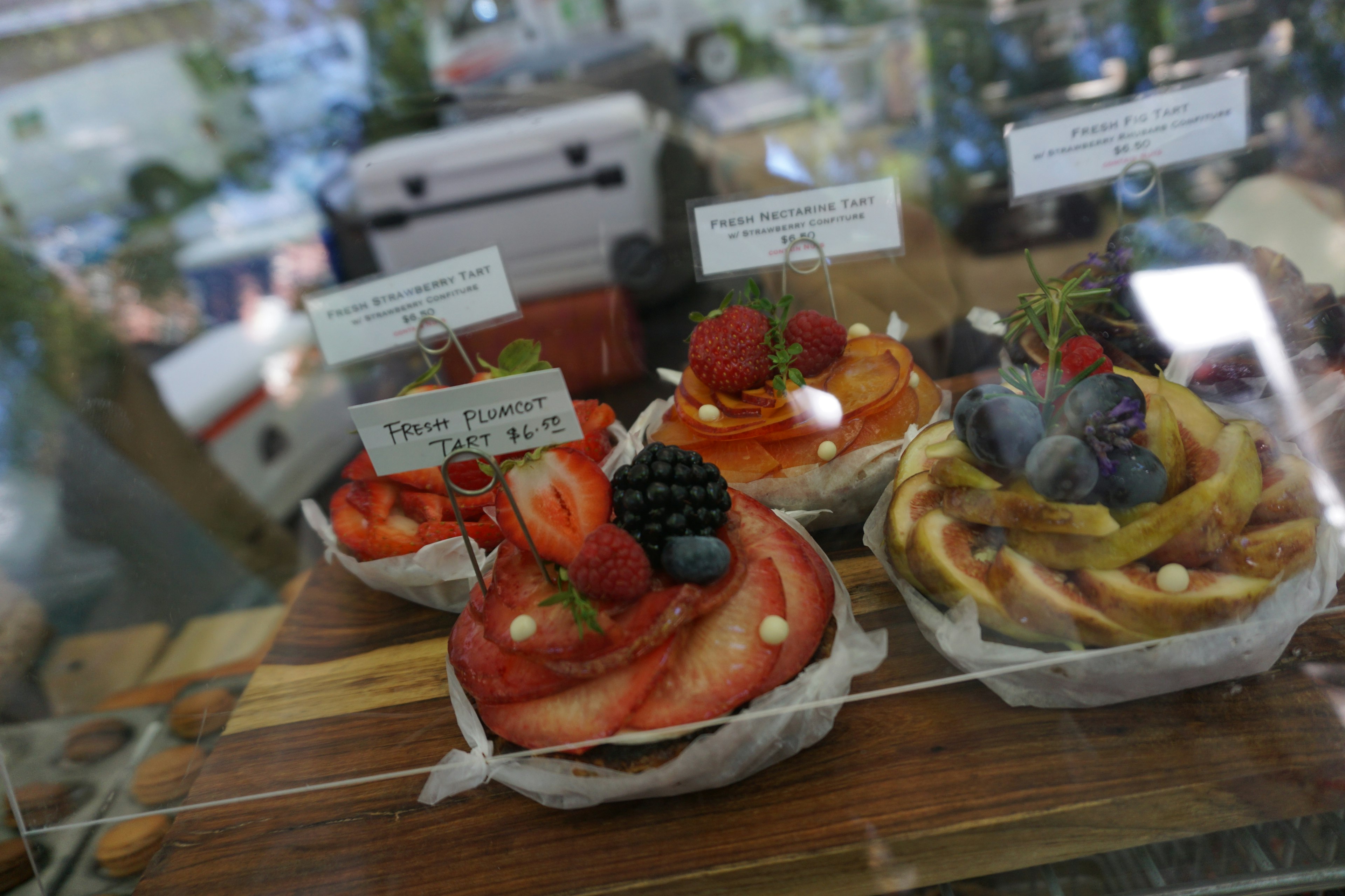 Colorful fruit tarts displayed in a glass case