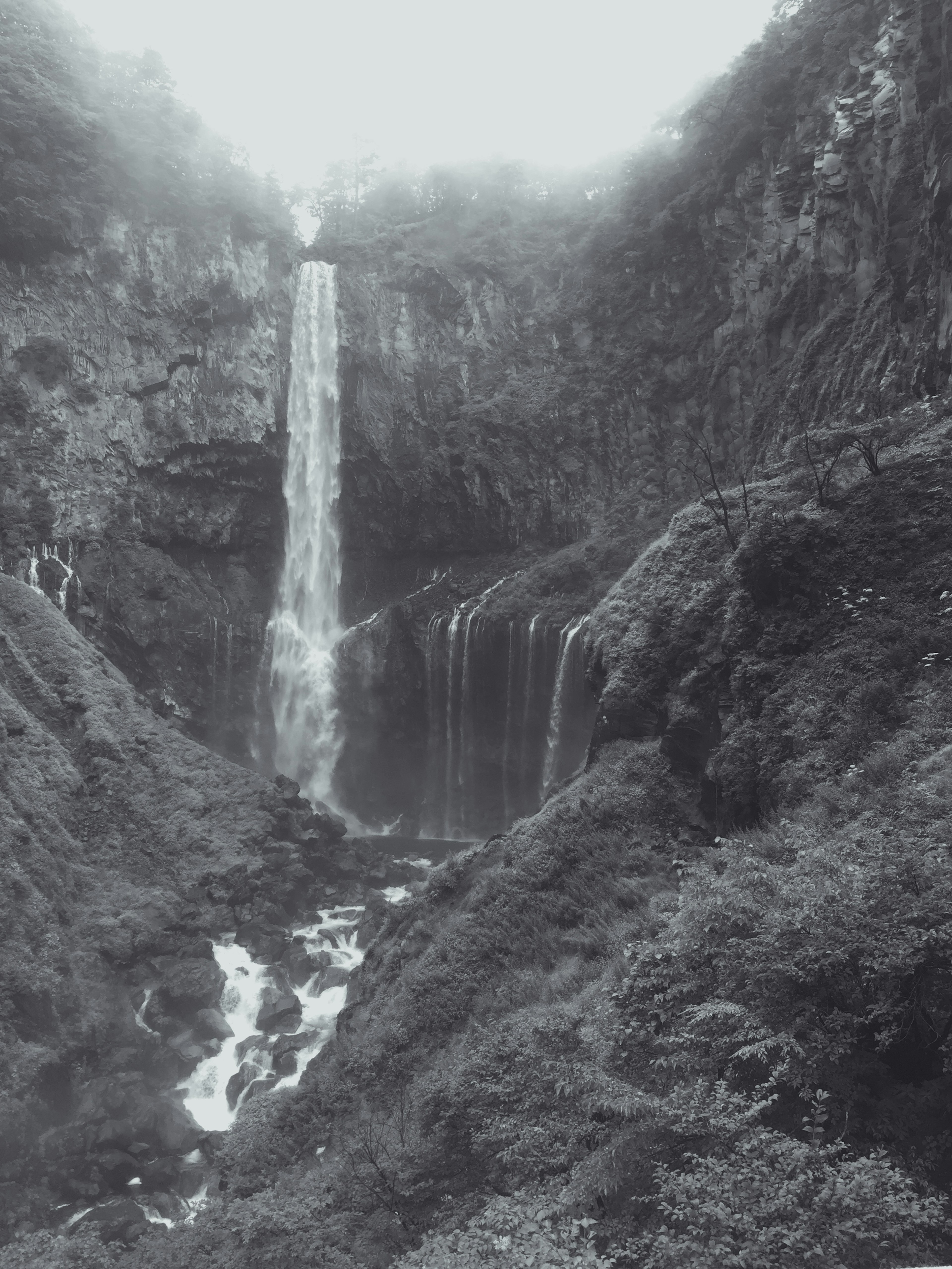 Une cascade tombant entourée de rochers et de verdure