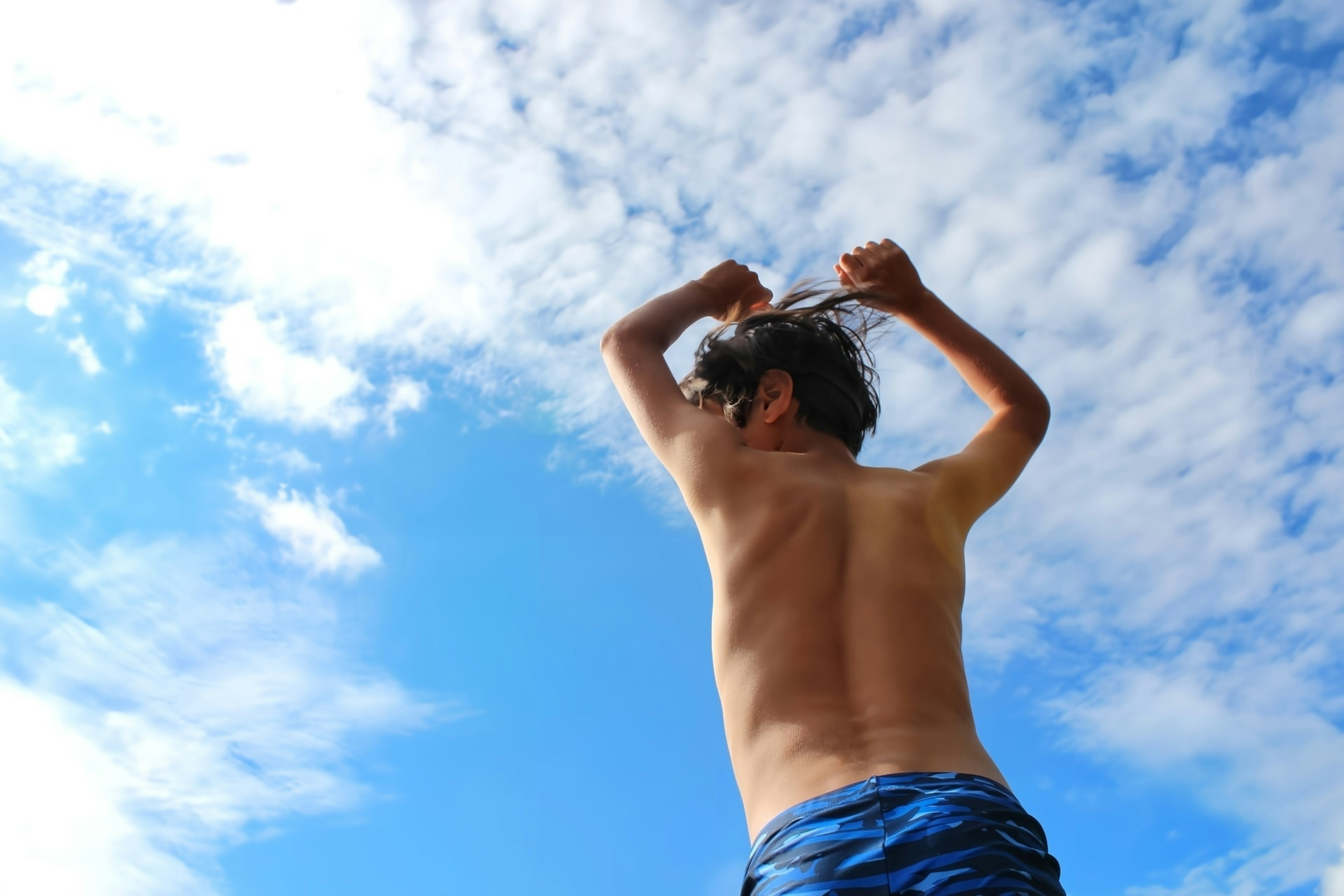 Homme attachant ses cheveux sous un ciel bleu