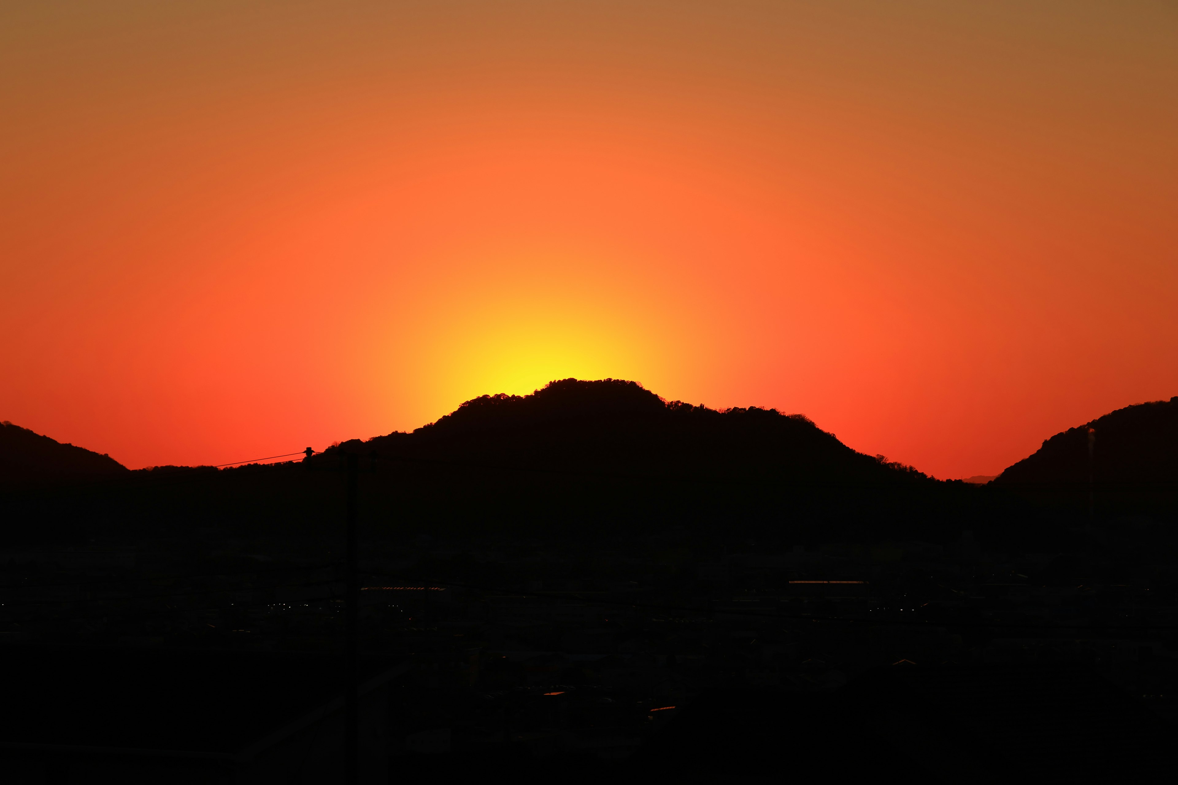 Sunset behind a mountain with vibrant orange hues