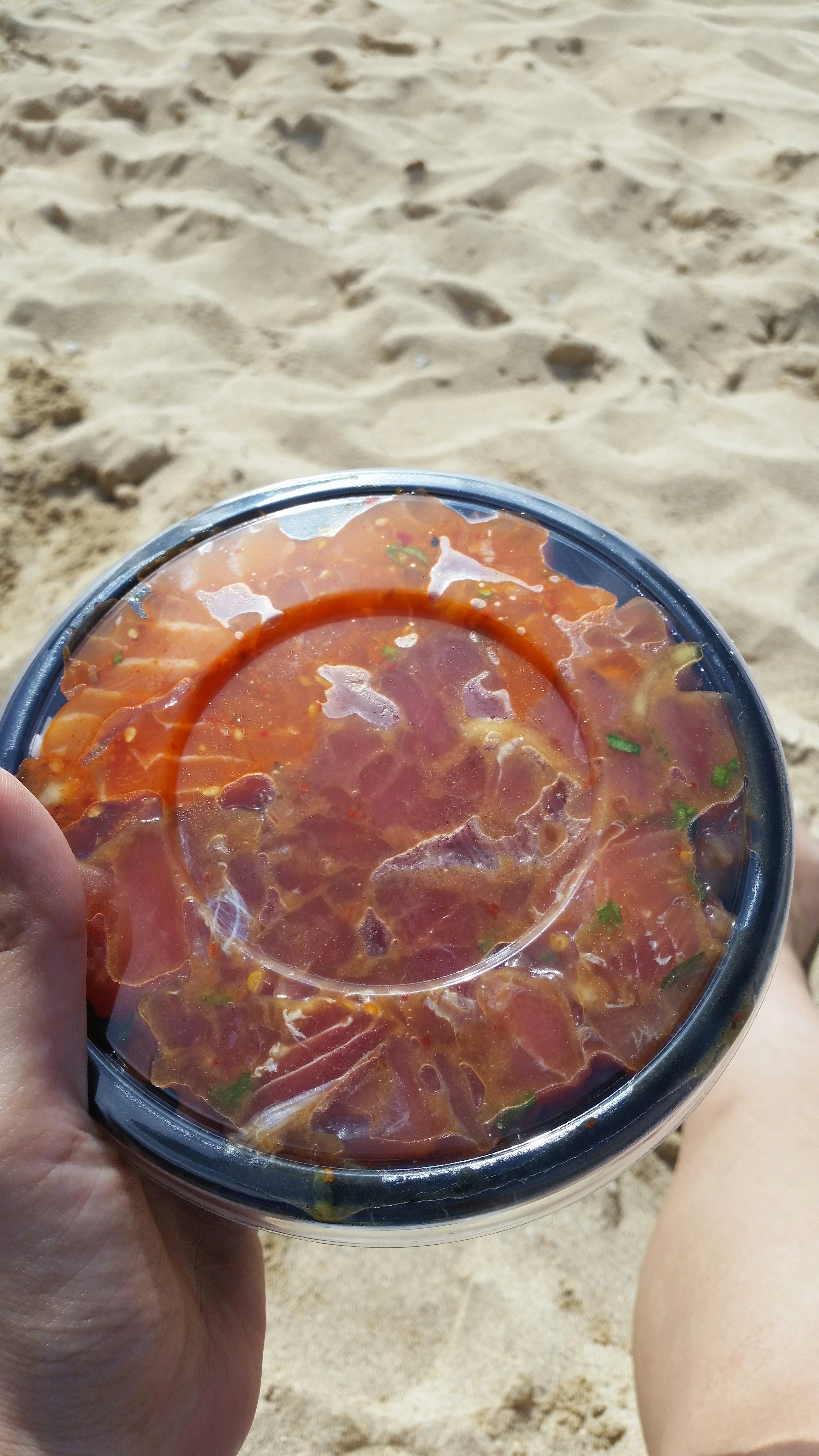 Un recipiente de sashimi fresco sostenido en la playa