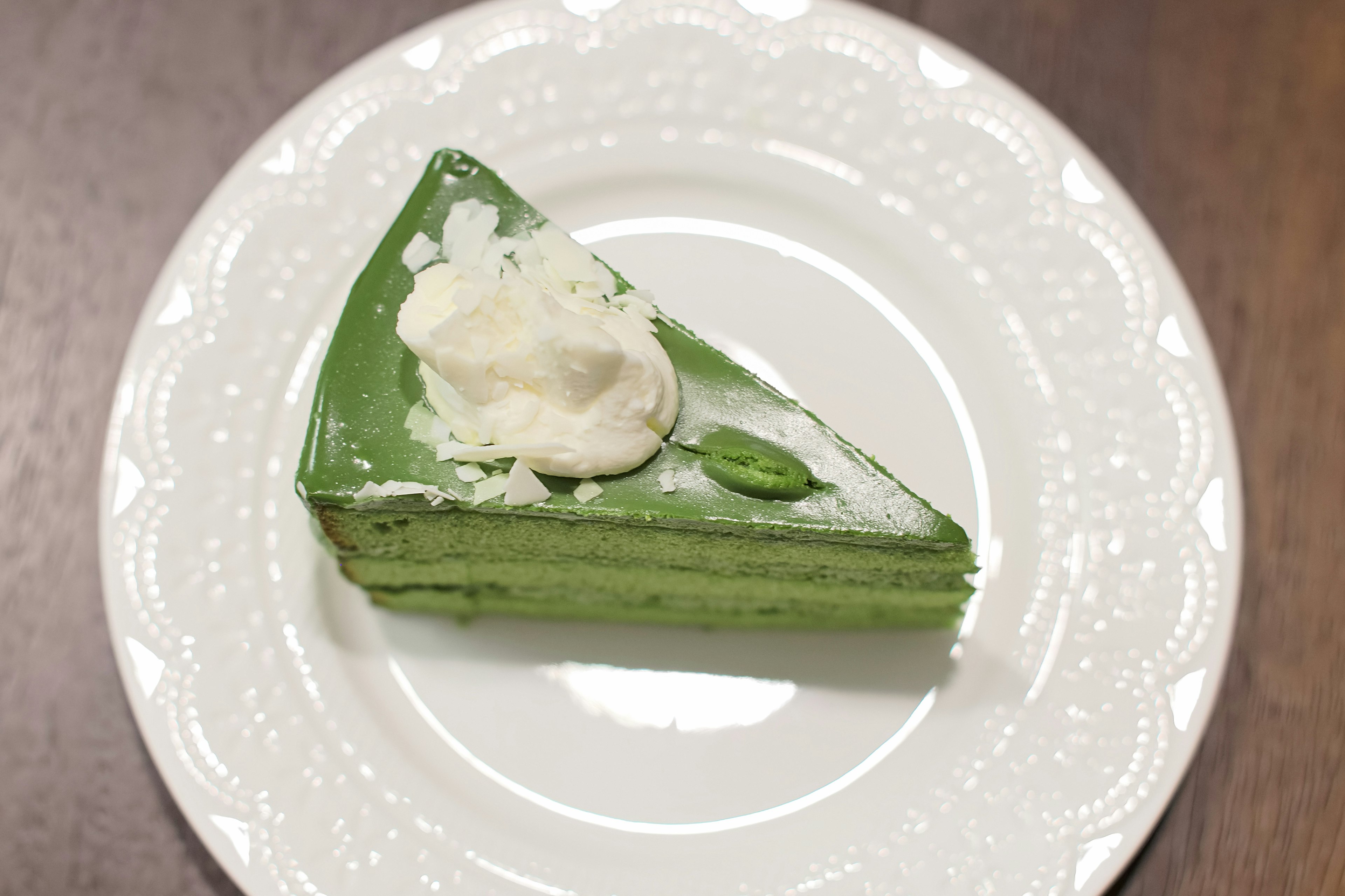 Slice of matcha cake topped with cream