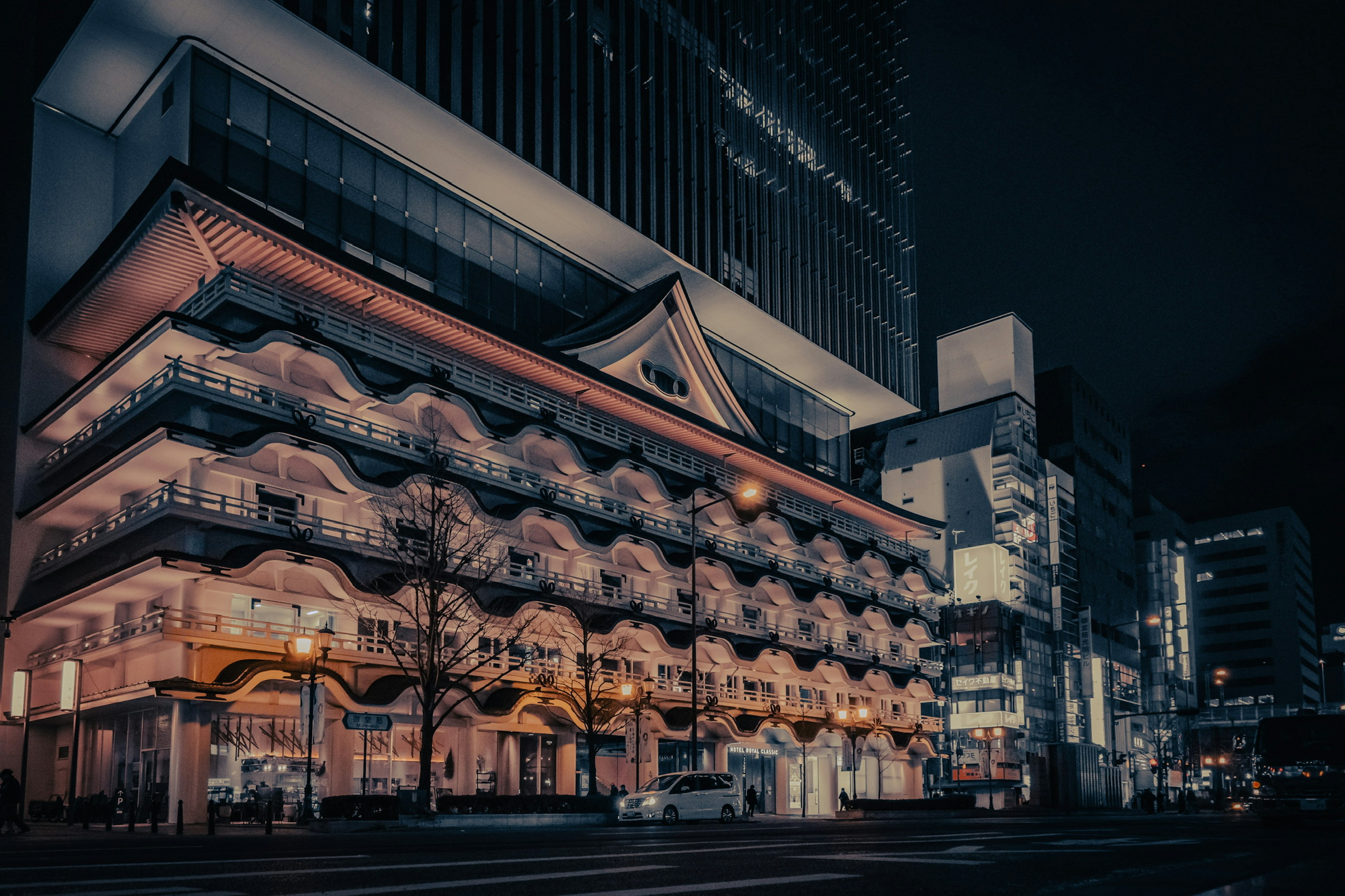 Traditional Japanese architecture illuminated at night with modern buildings