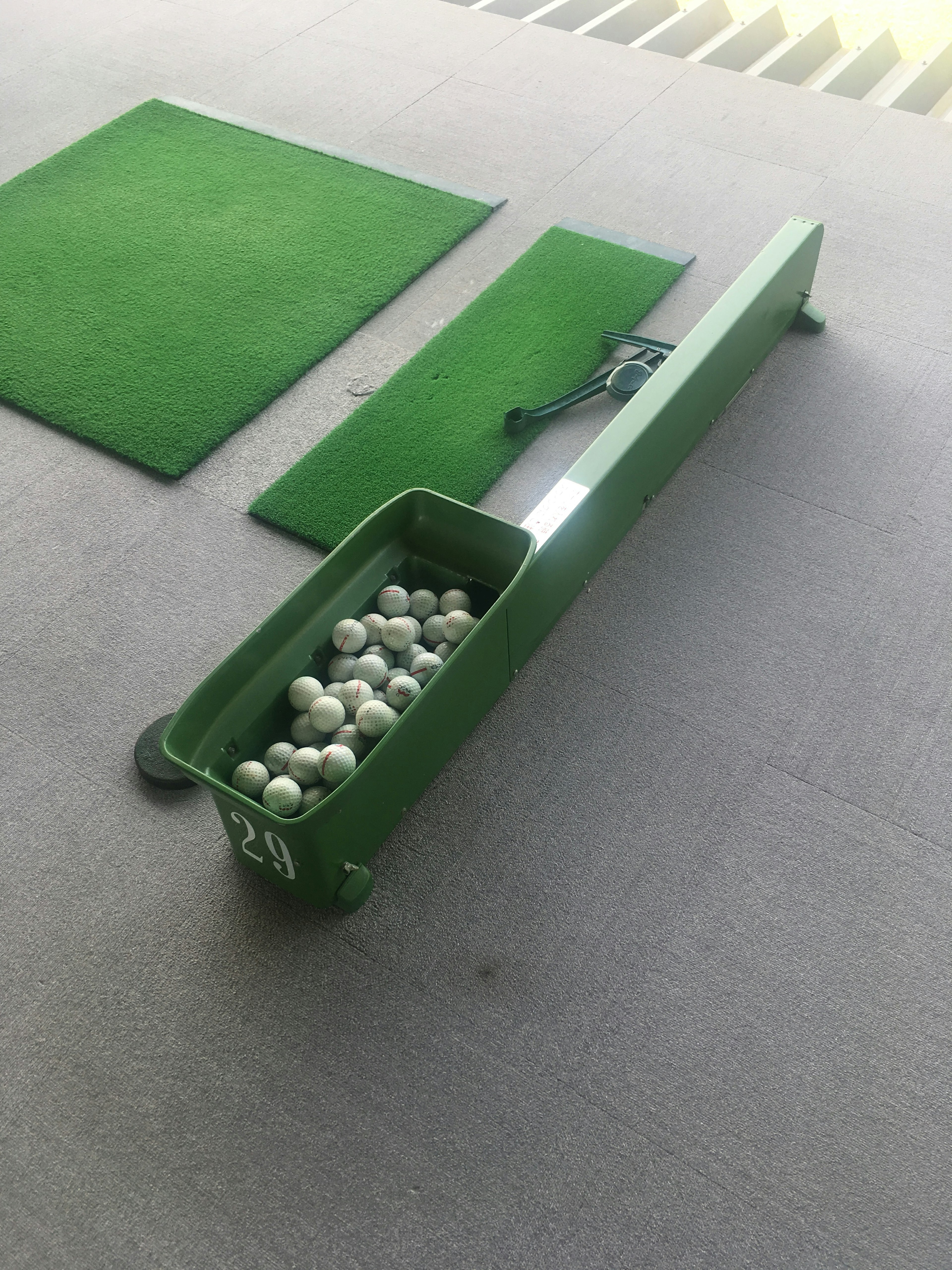 Eine Szene in einem Golfübungsgelände mit einem grünen Balltray und Matten