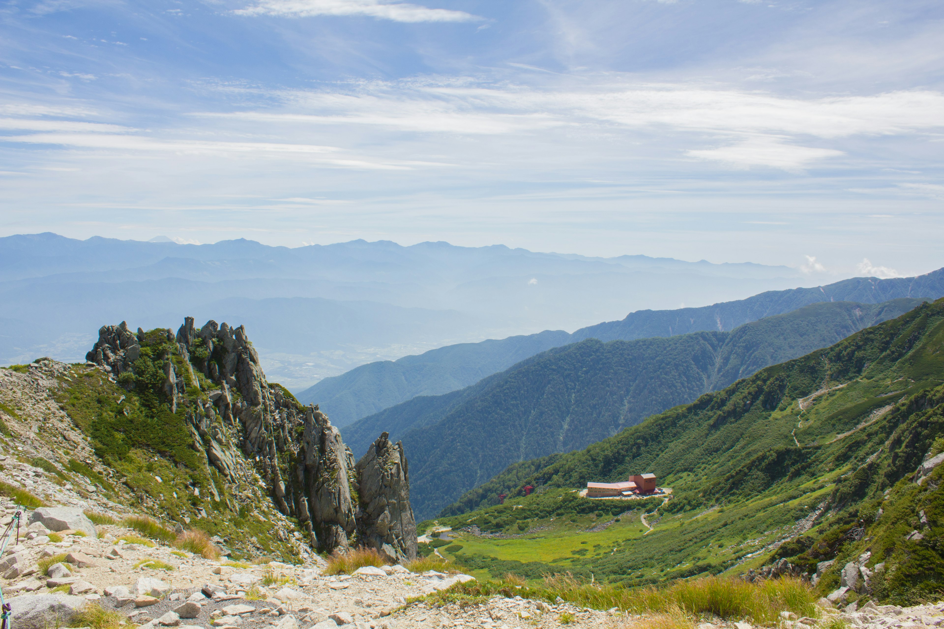 Berglandschaft mit grünem Tal und einer roten Hütte