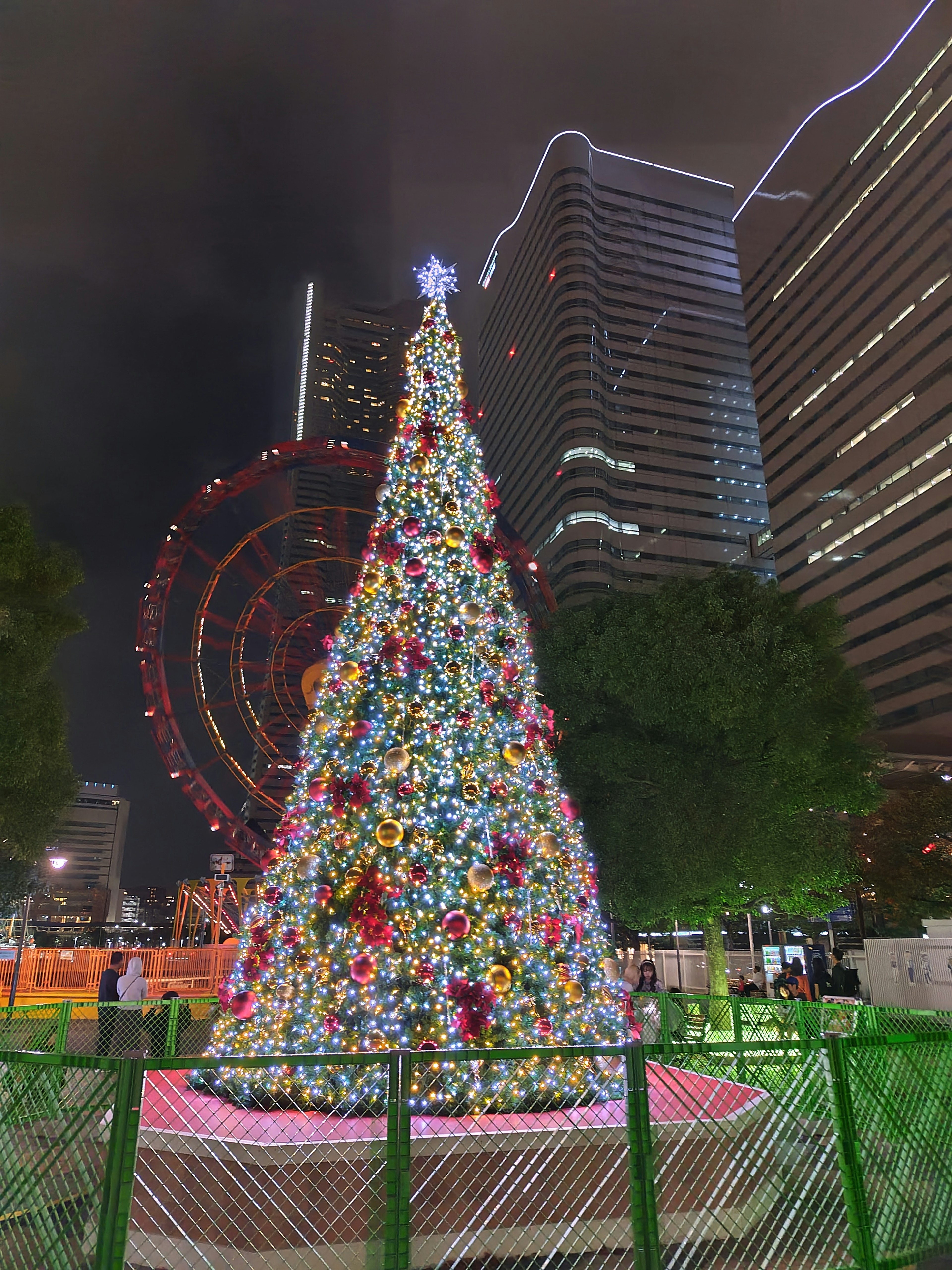 Bunter Weihnachtsbaum, der nachts beleuchtet ist, mit Wolkenkratzern im Hintergrund