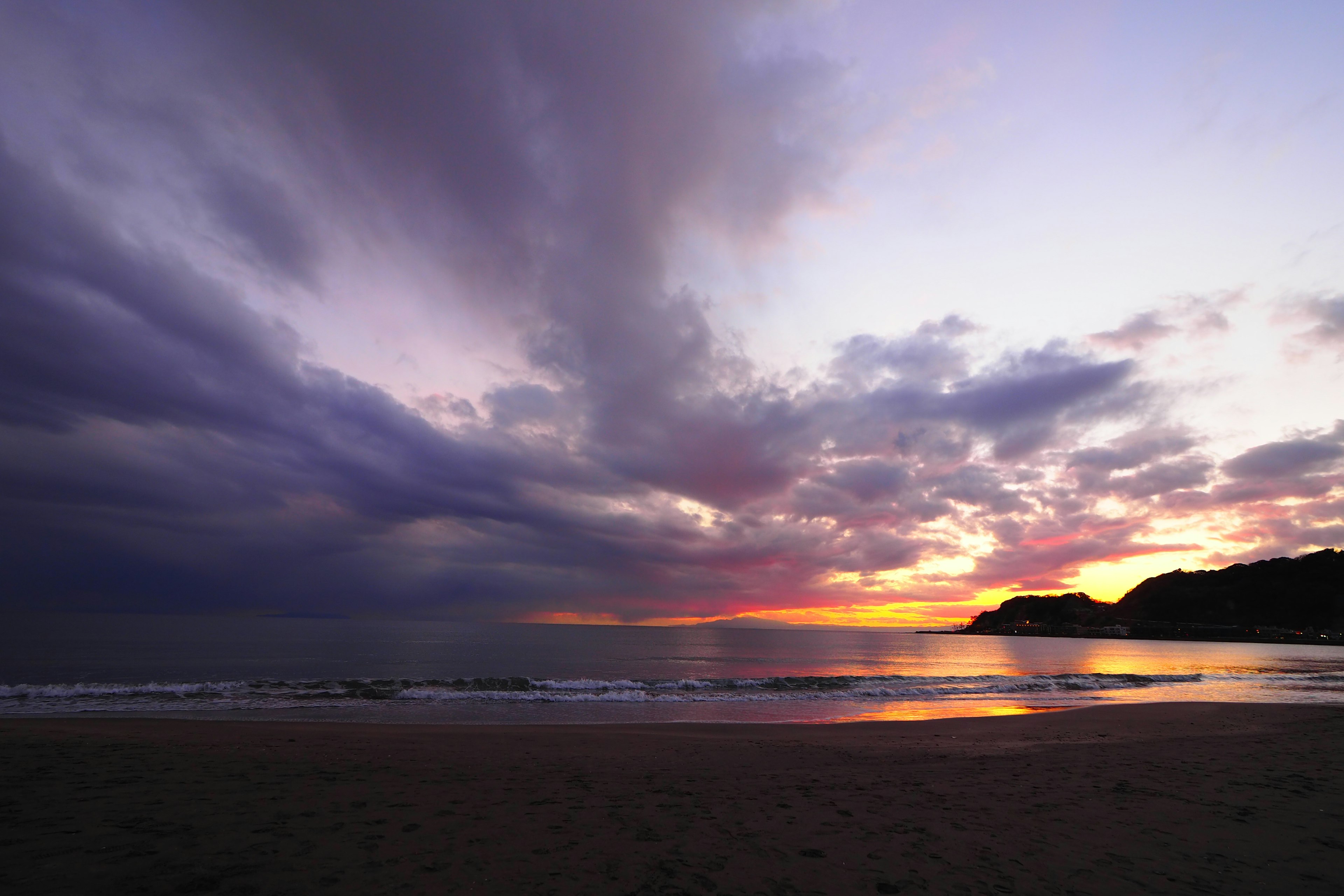 Pemandangan matahari terbenam yang menakjubkan di pantai dengan awan dramatis