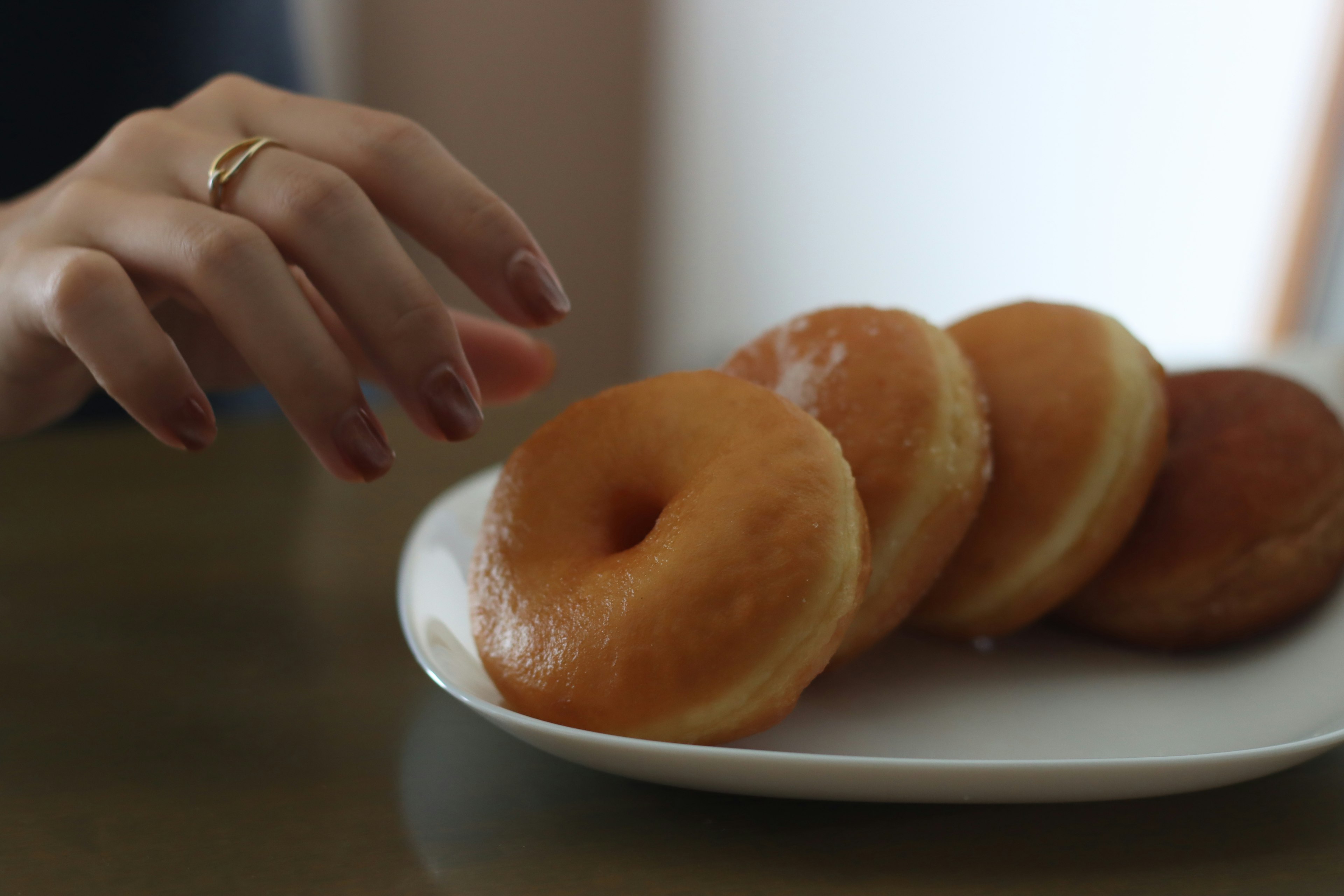 Hand greift nach Donuts auf einem Teller