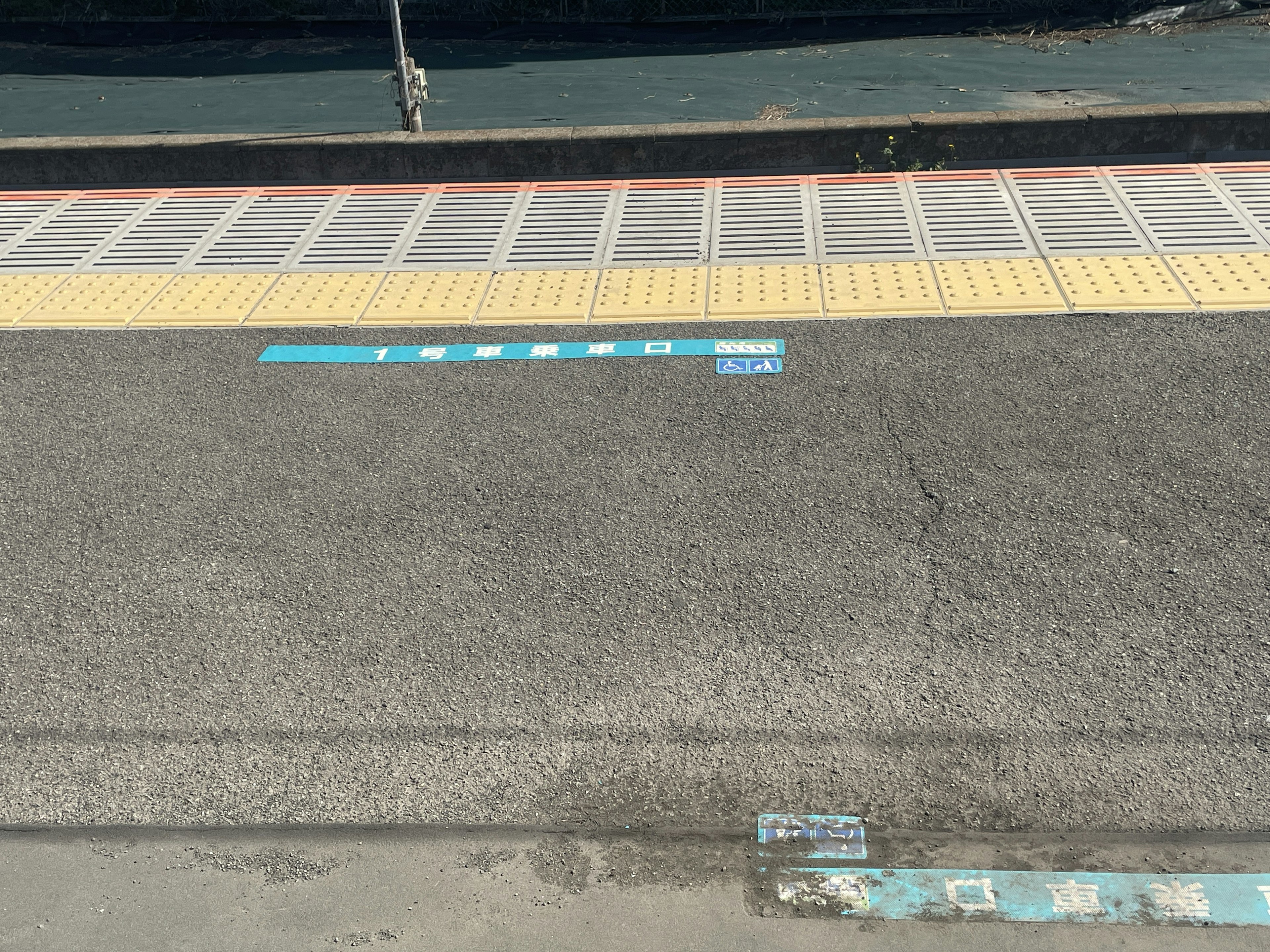 Línea azul y baldosas amarillas en una plataforma de tren