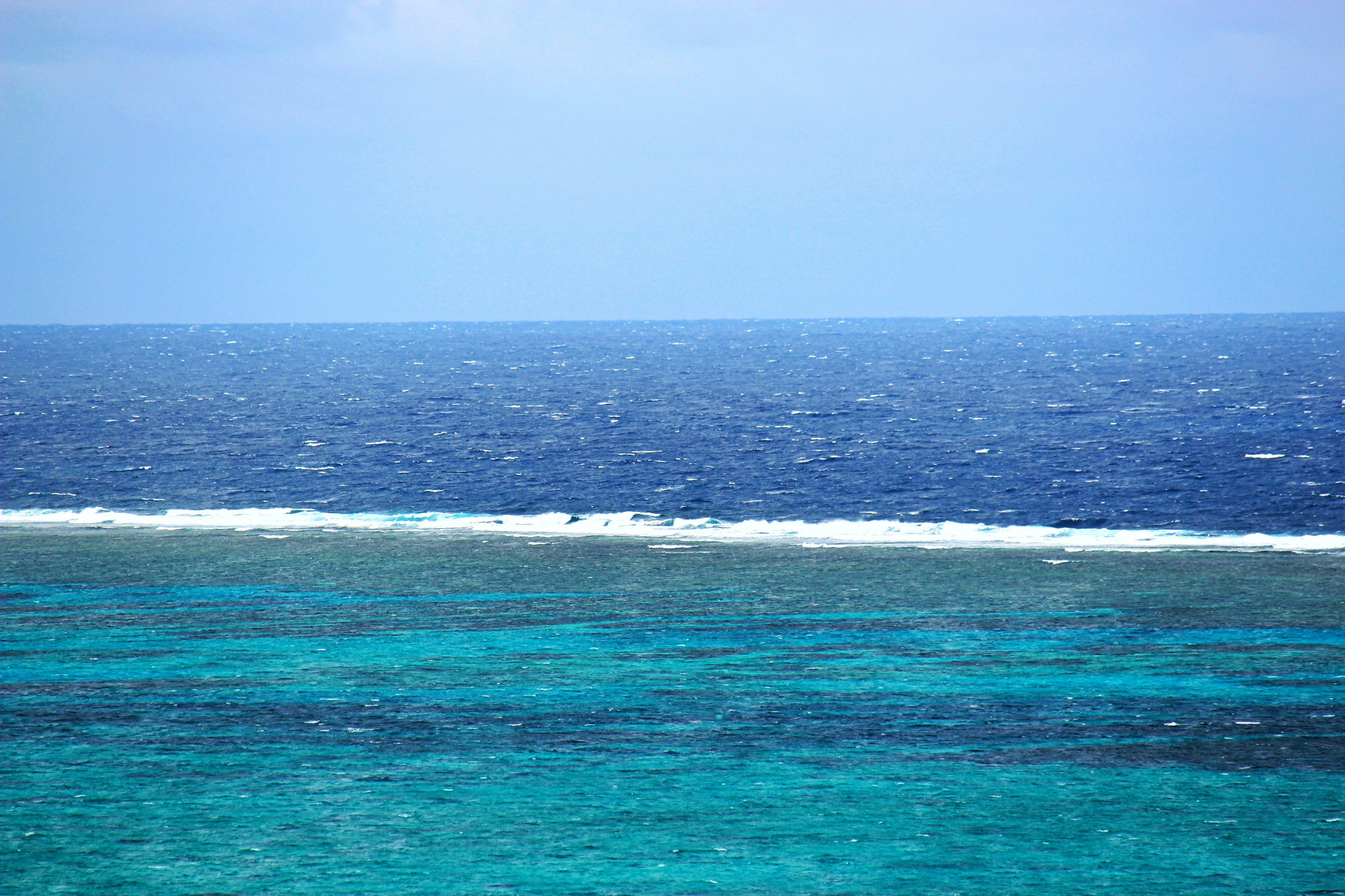 Panoramablick auf den blauen Ozean und den Himmel, der von tiefblau zu smaragdgrünem Wasser wechselt