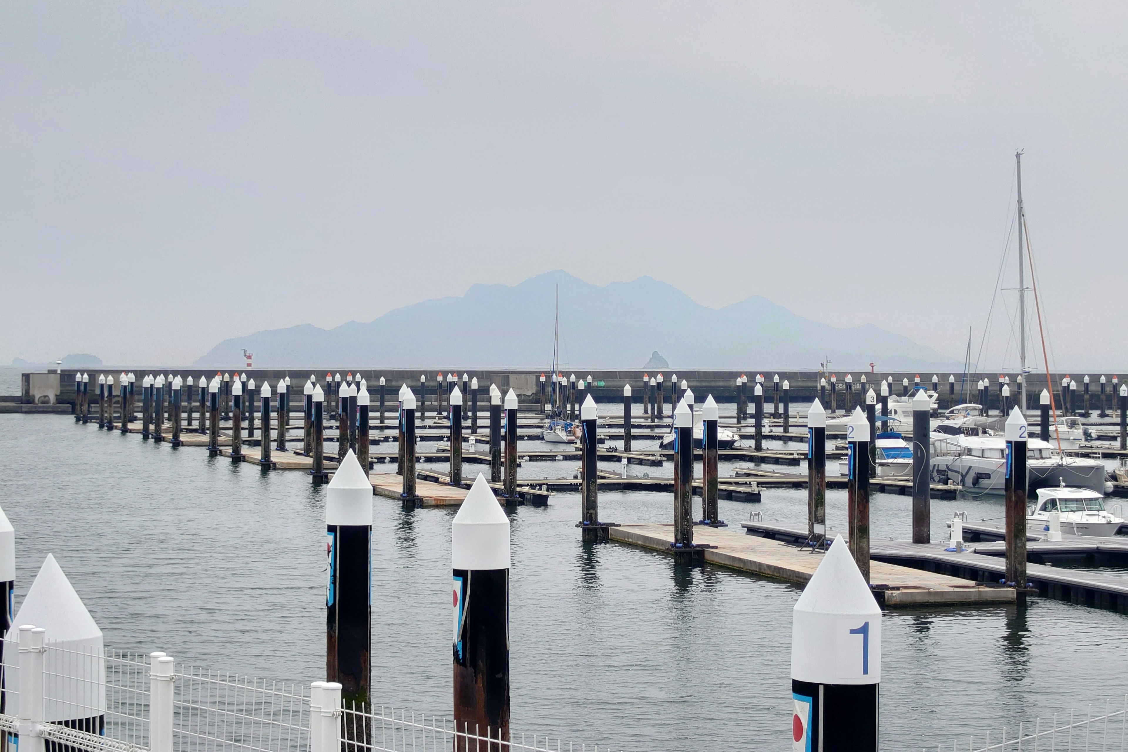 Harbor view with moored boats in foggy weather distant mountains visible