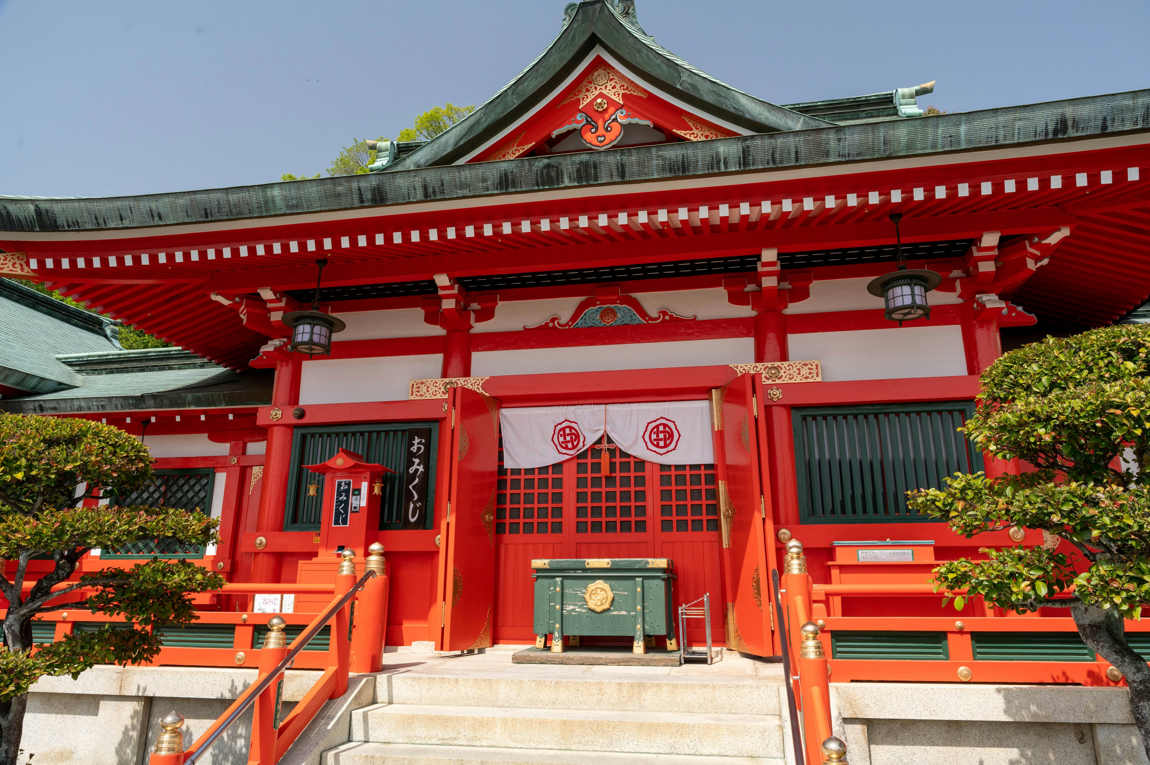 Sanctuaire traditionnel rouge avec une architecture complexe et une verdure luxuriante