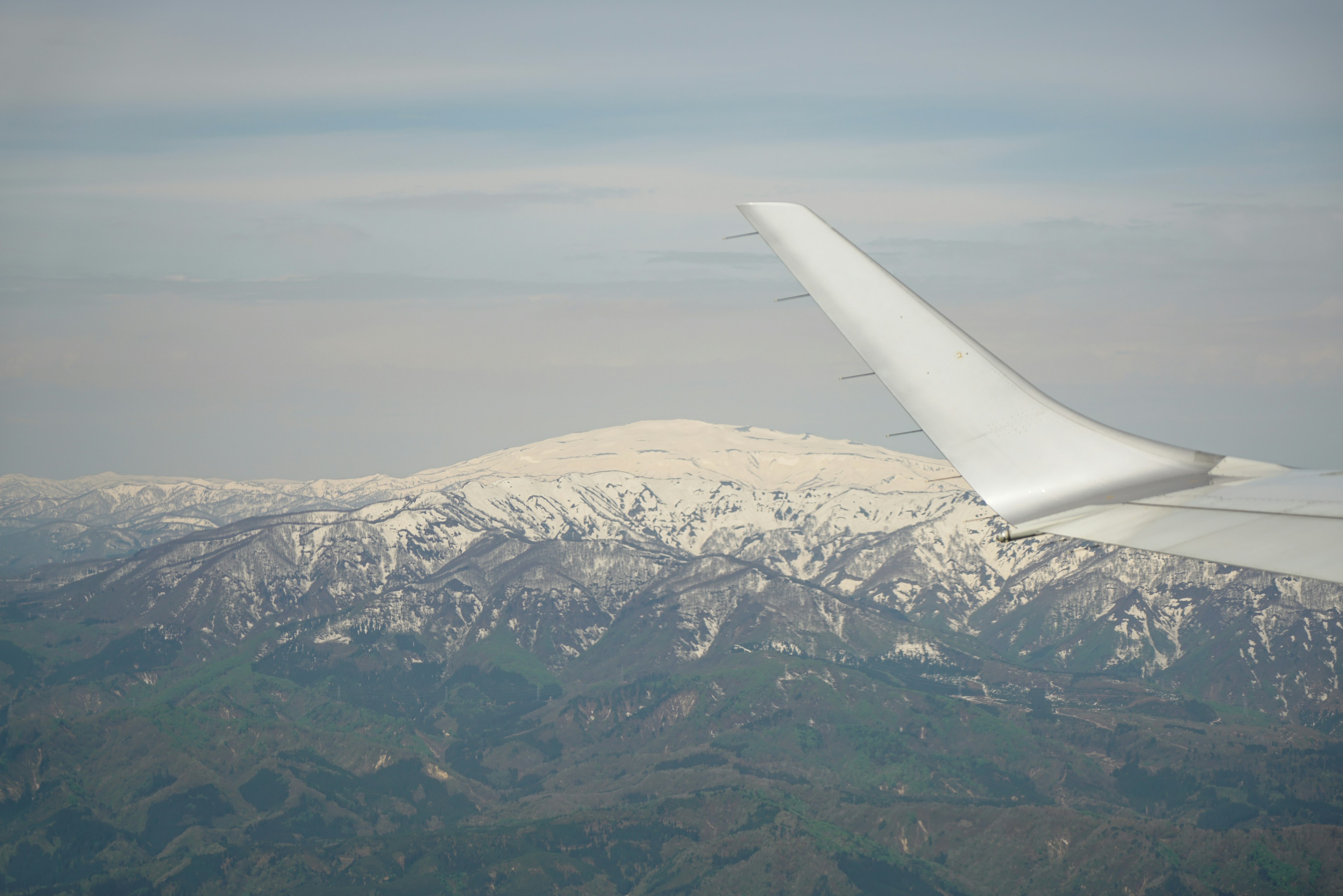 飛行機の翼と雪に覆われた山々の風景