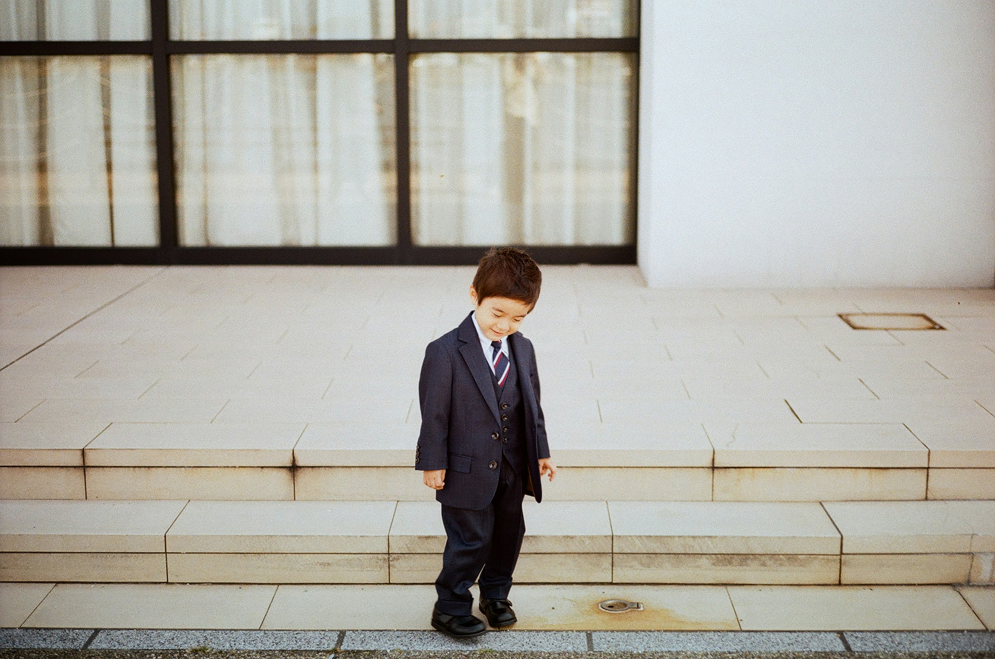 スーツを着た少年が階段の前に立っている