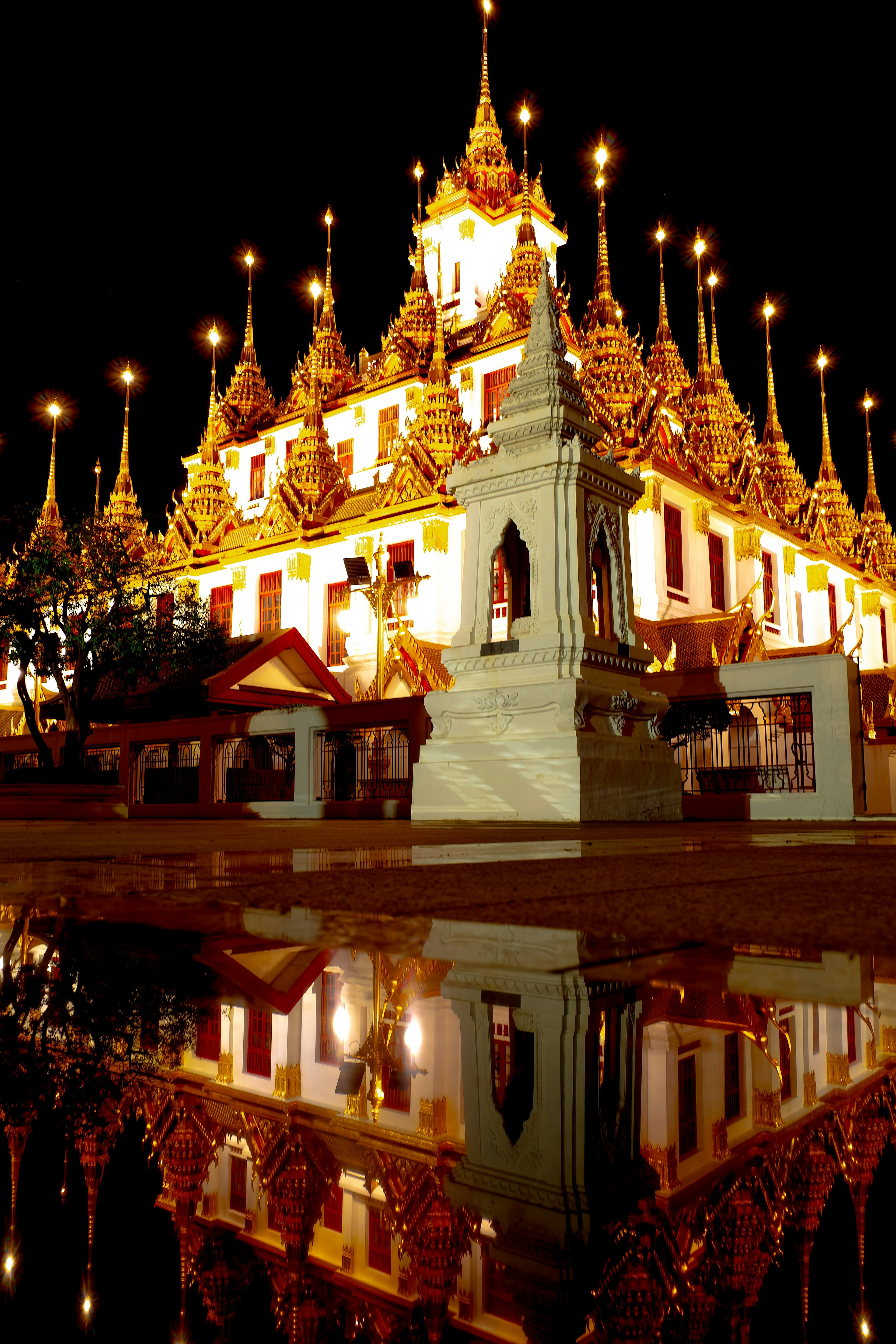 Beau temple la nuit avec des décorations dorées se réfléchissant dans l'eau