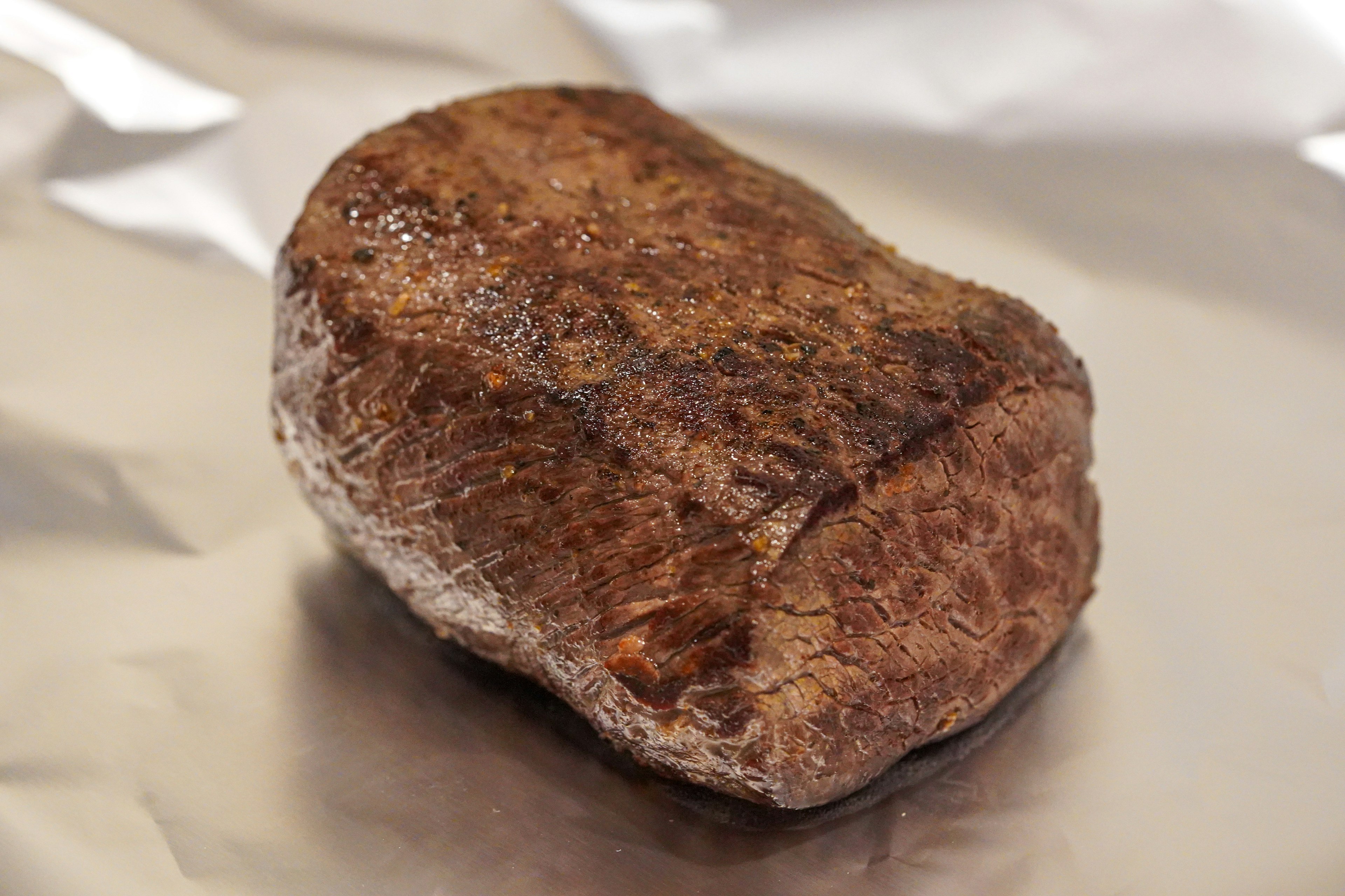 A browned piece of meat resting on aluminum foil