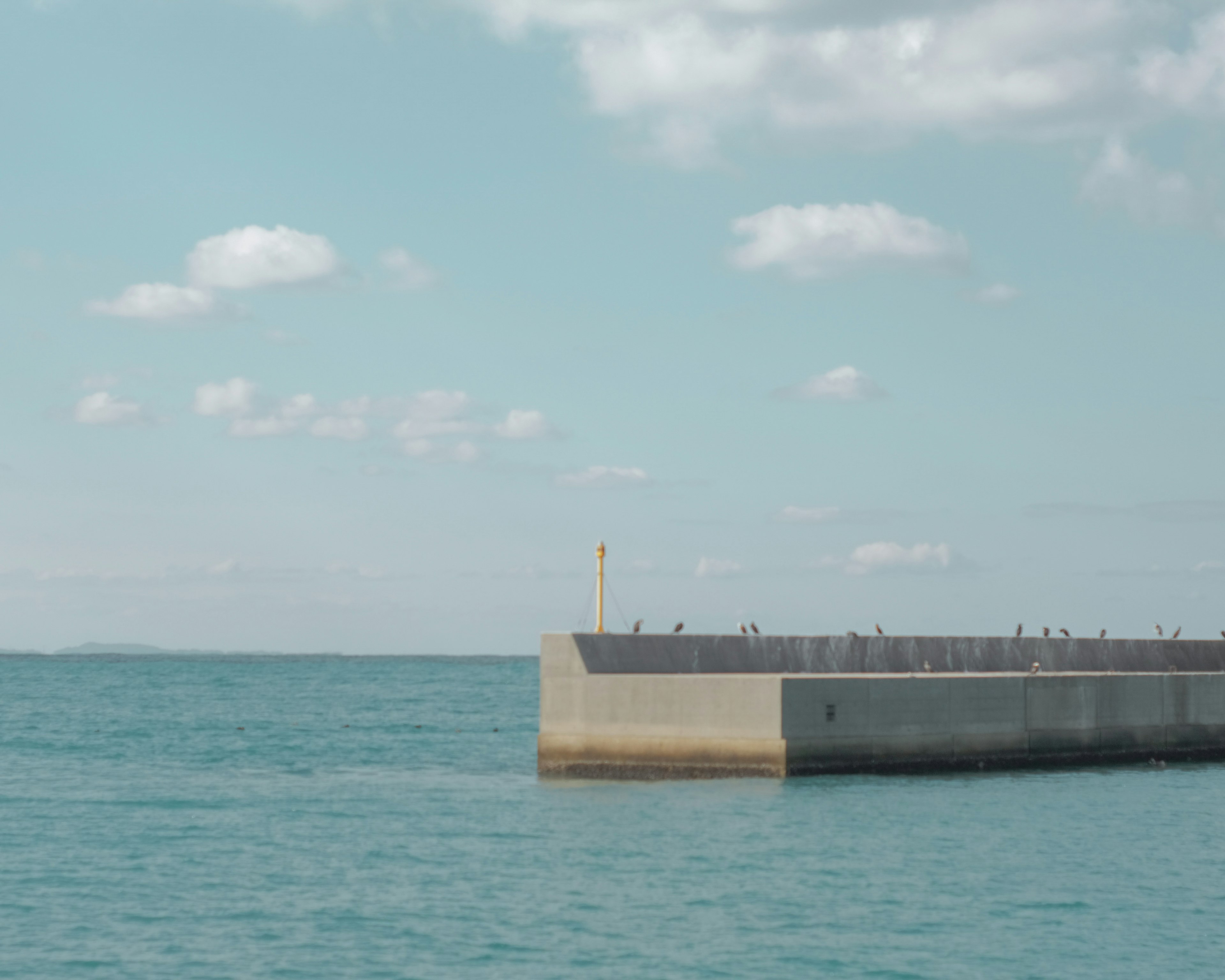 青い海と晴れた空に浮かぶ防波堤の風景