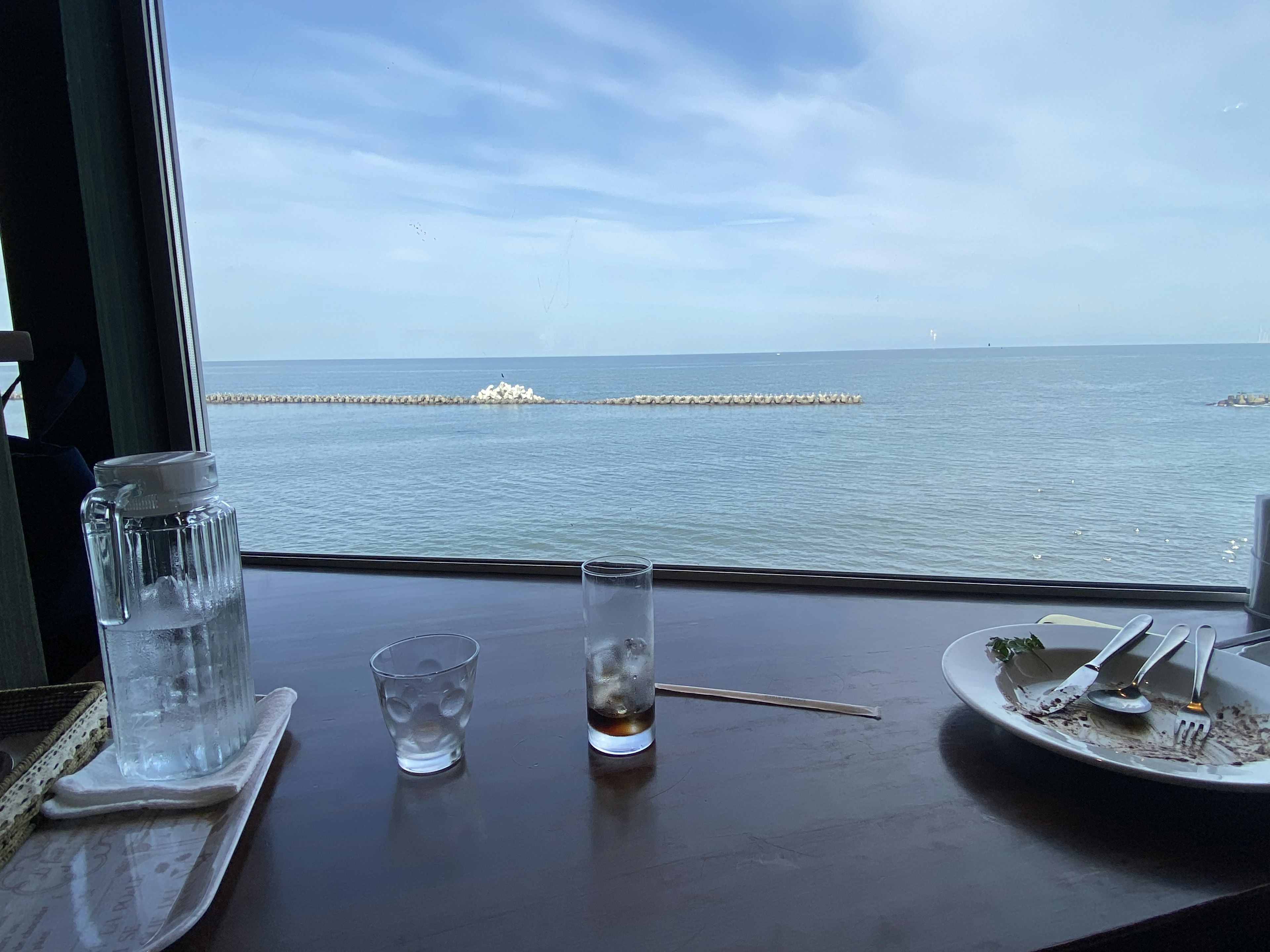 Tisch mit Gläsern und Teller mit Blick auf das Meer