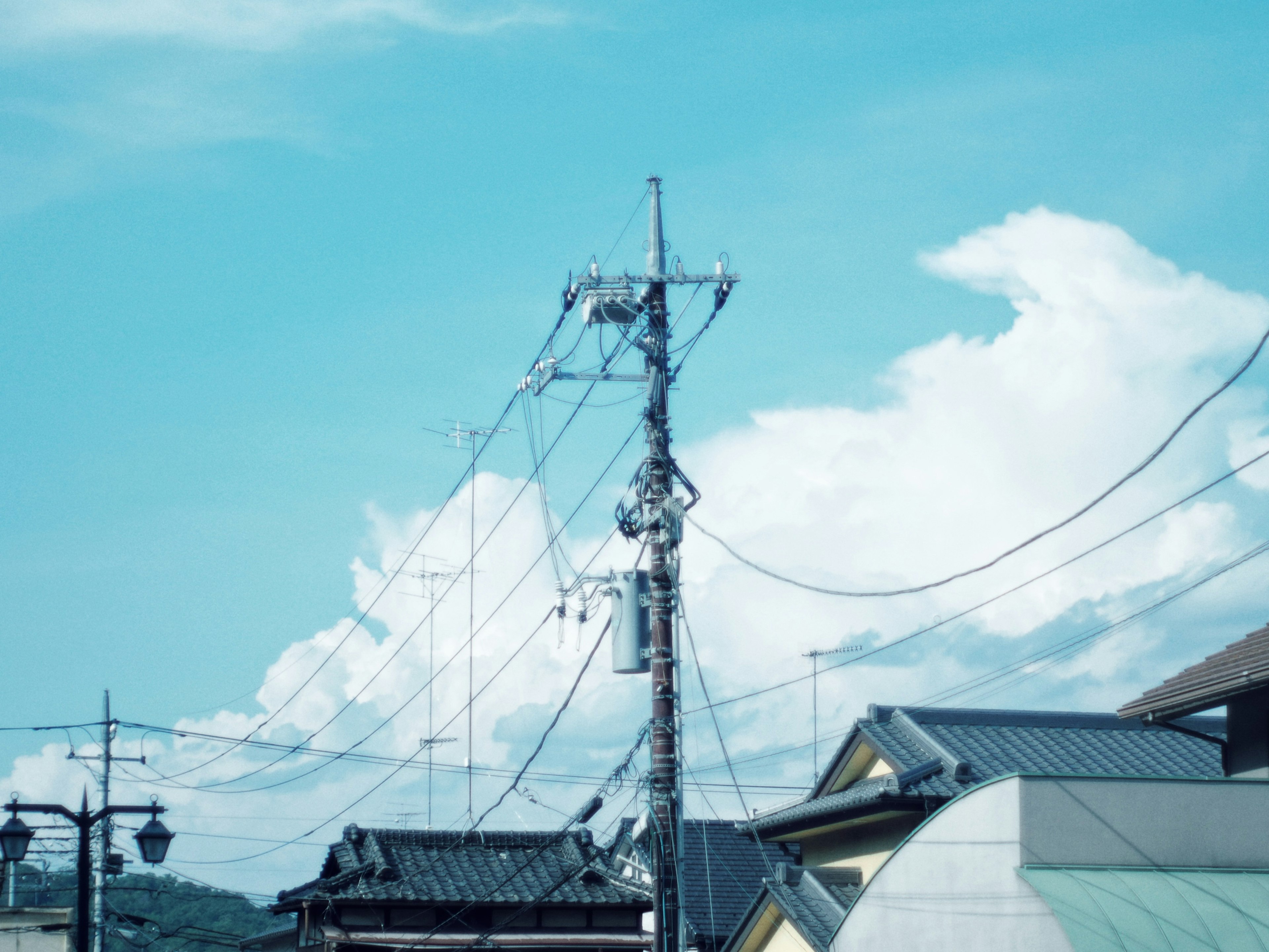 Vue de poteaux électriques et de fils contre un ciel bleu avec des nuages blancs