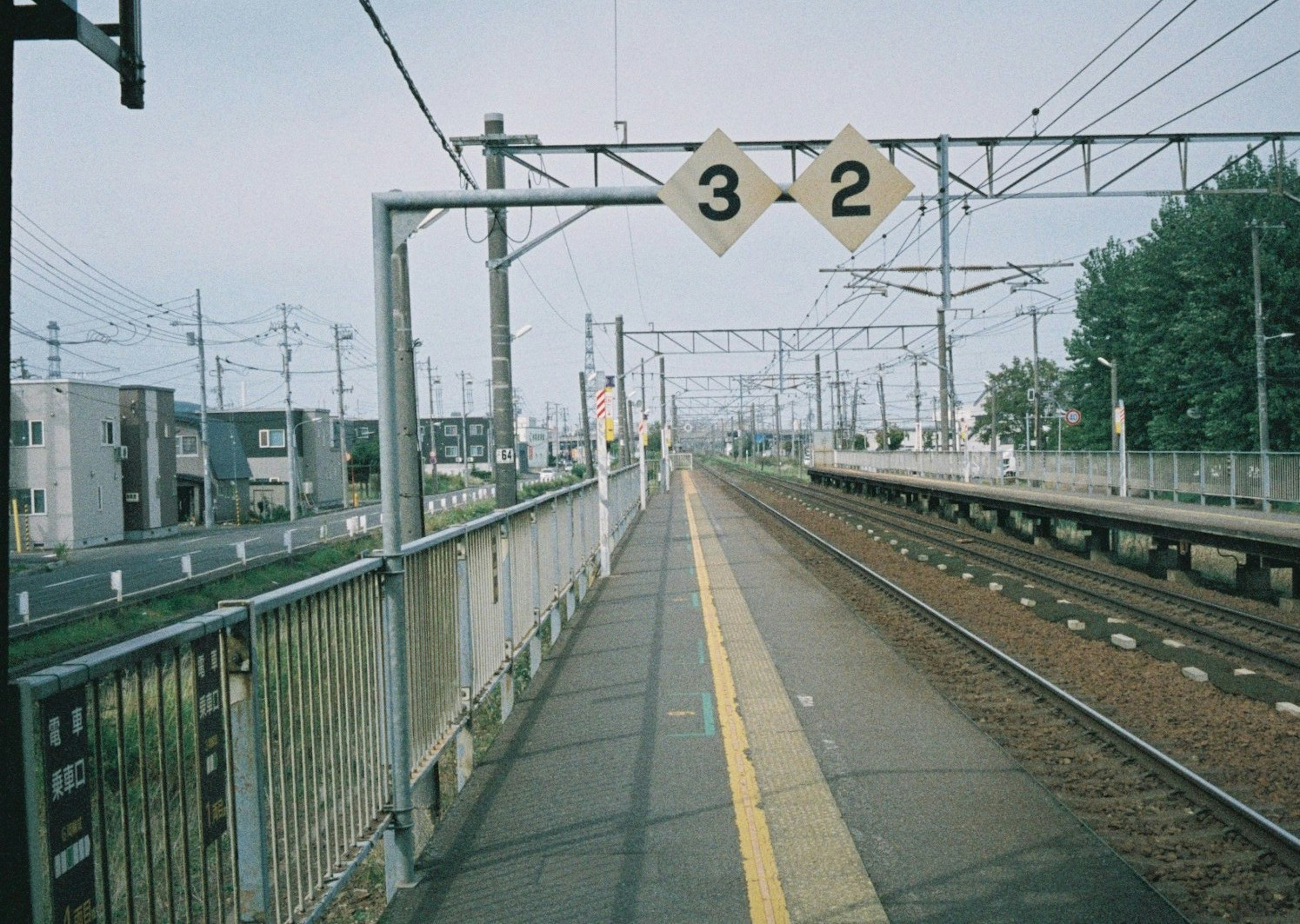 駅のプラットフォームに立つ線路の風景、番号2と3の標識が見える