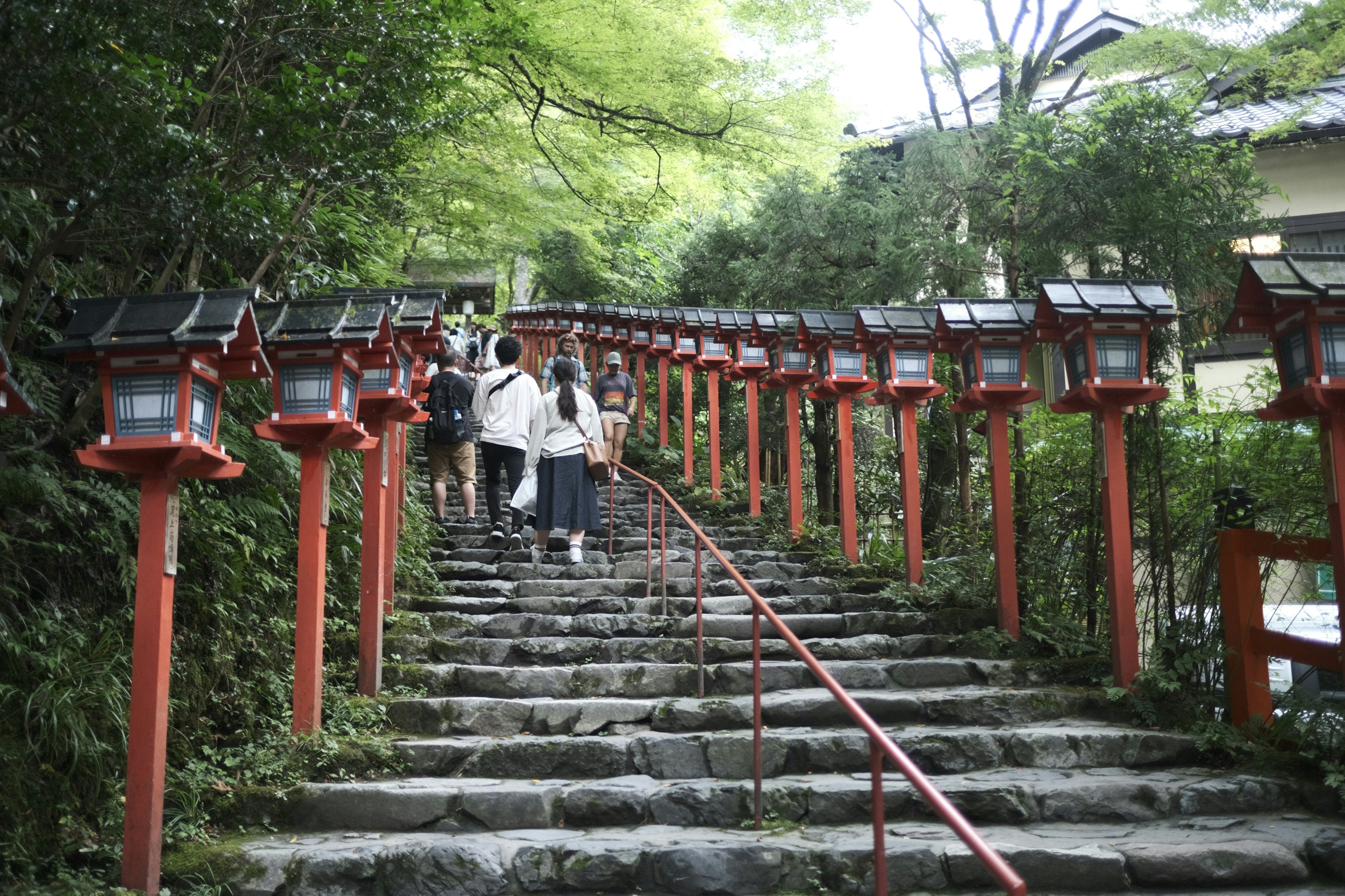 People walking up stone steps lined with red lanterns