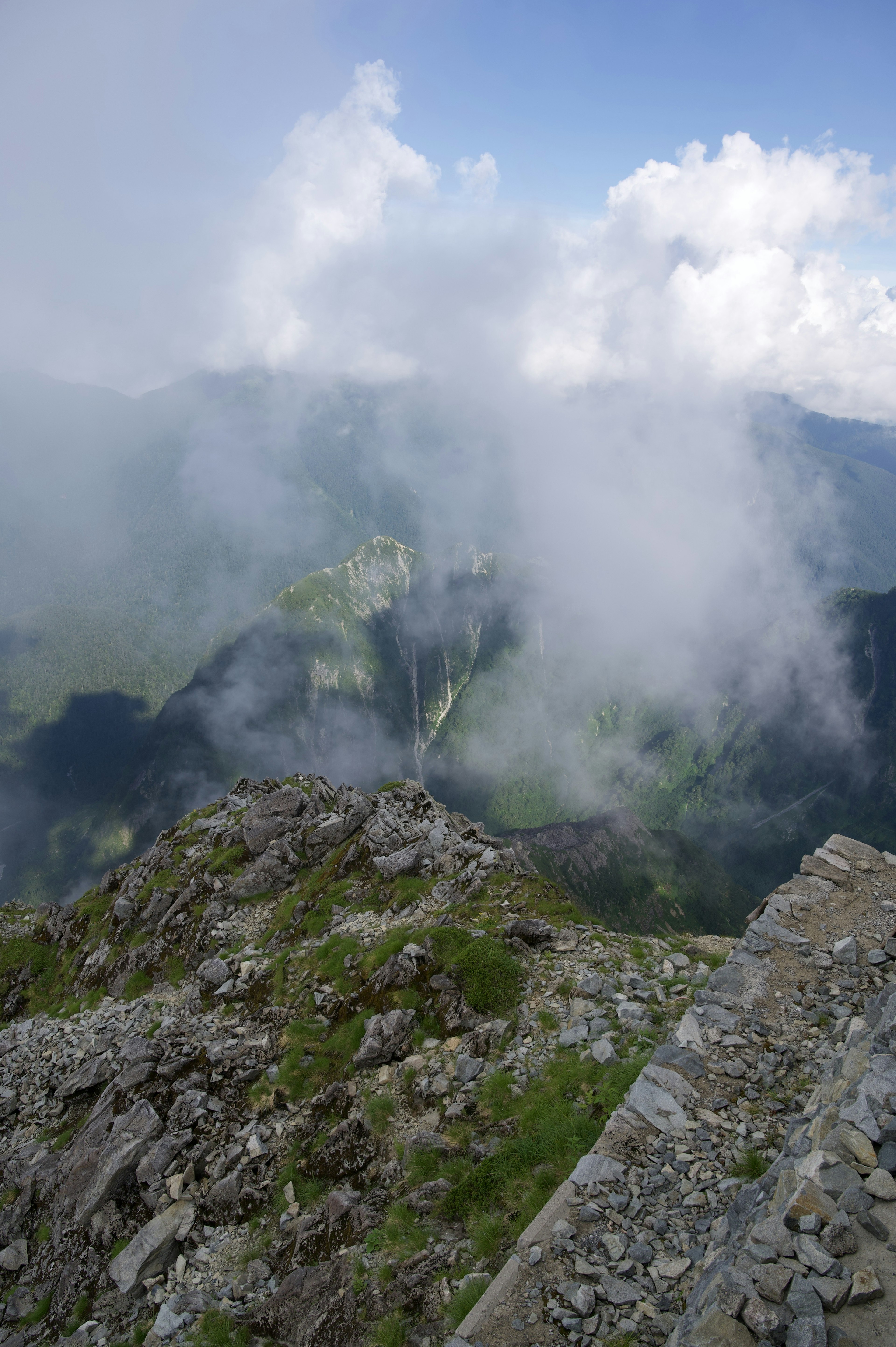 Vista desde un pico montañoso envuelto en niebla valles verdes y terreno rocoso