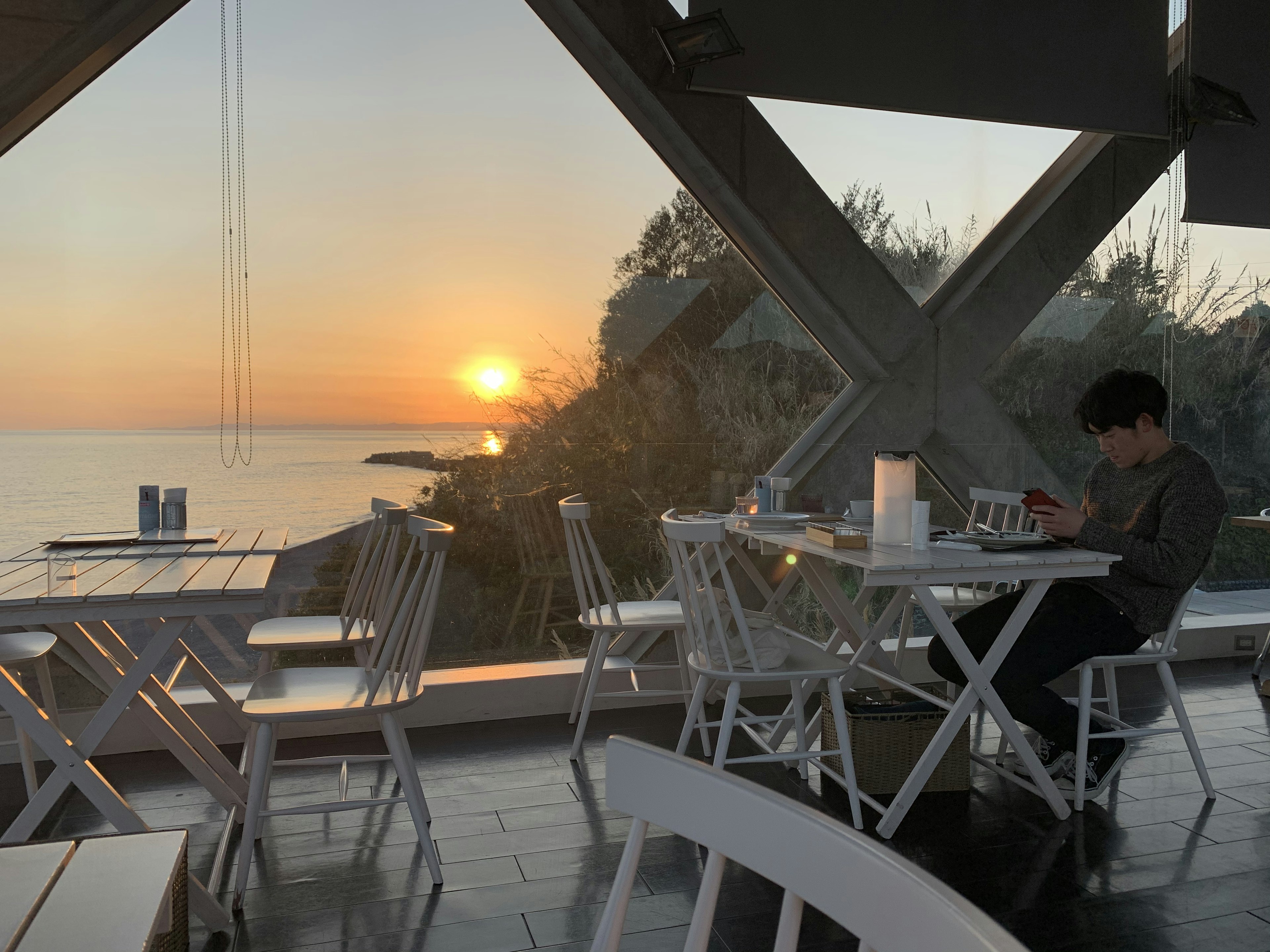 Interior of a cafe with a sunset over the sea in the background a customer enjoying the view