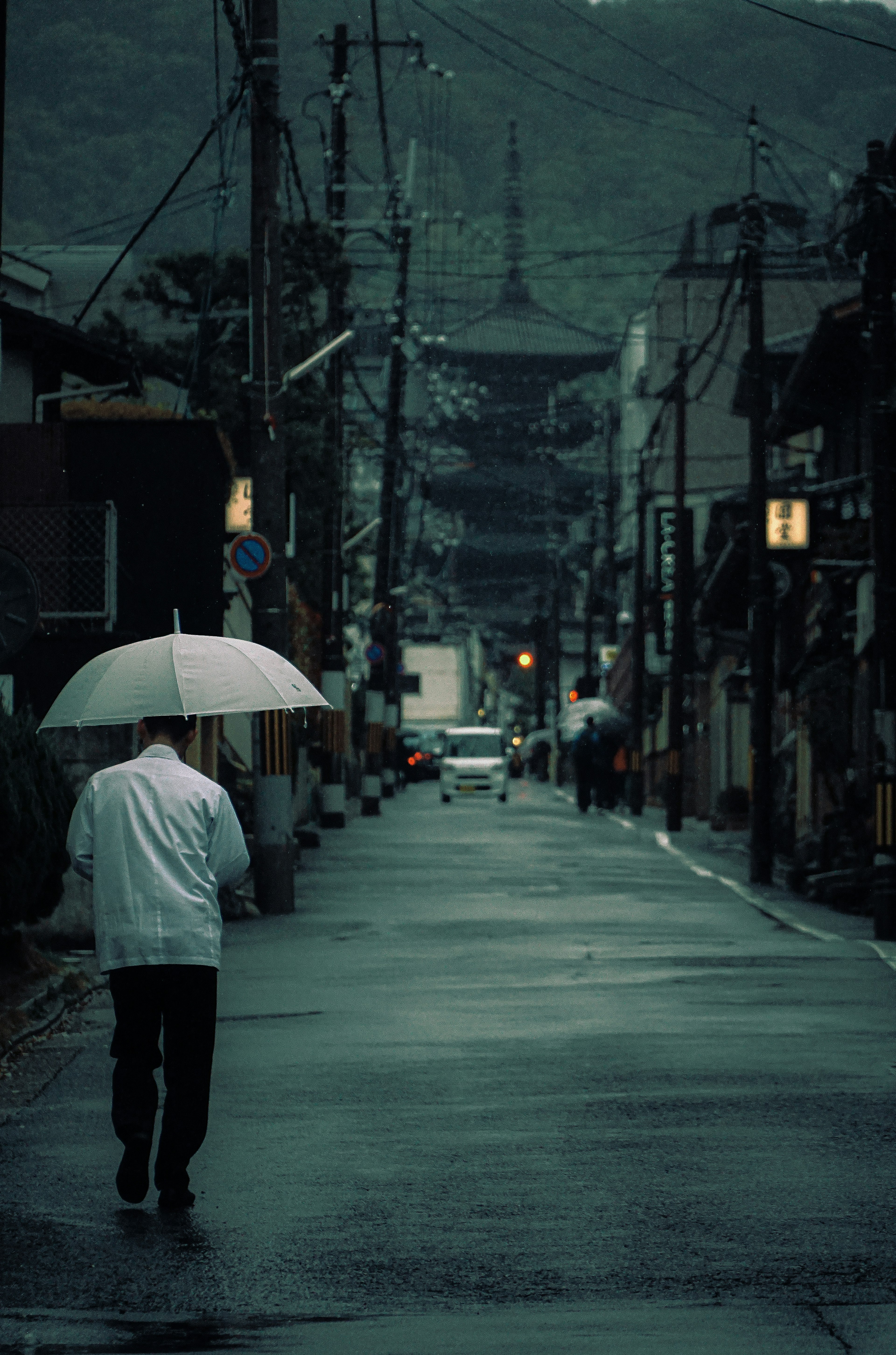A person walking with an umbrella in a quiet street during rain