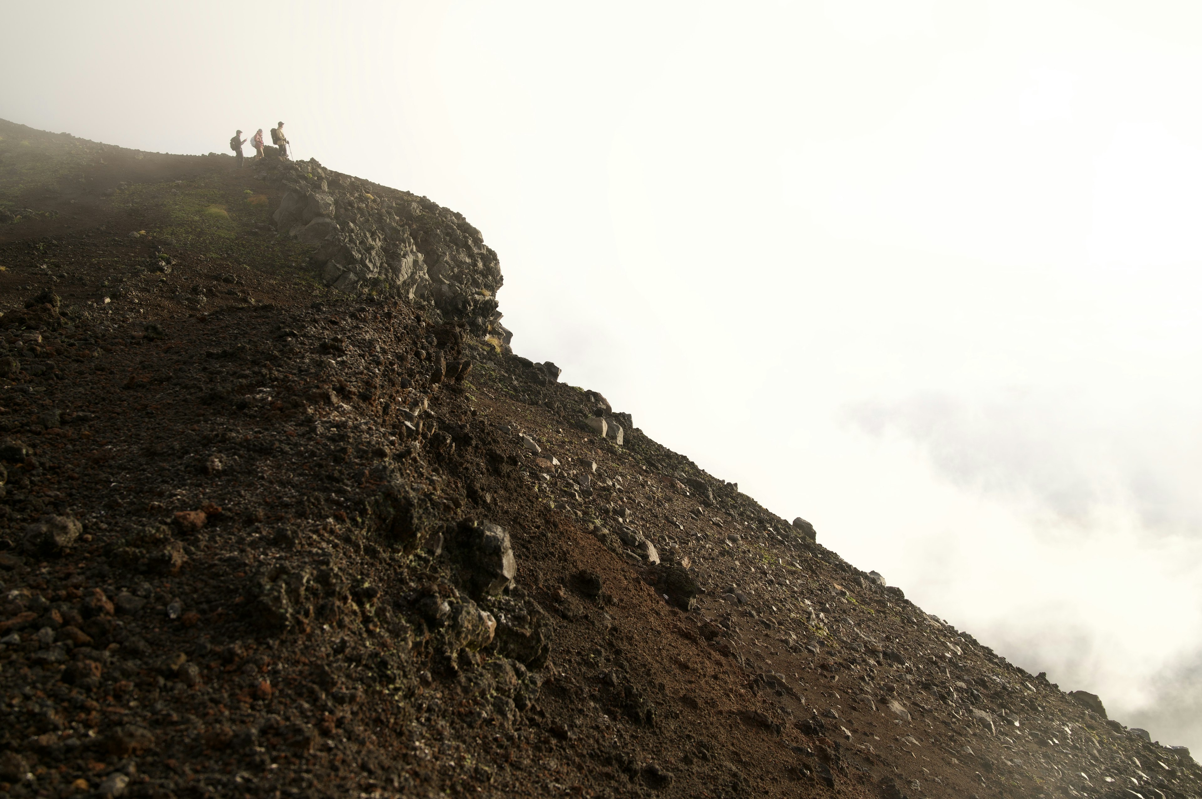 霧の中の山の頂上に立つ登山者たち