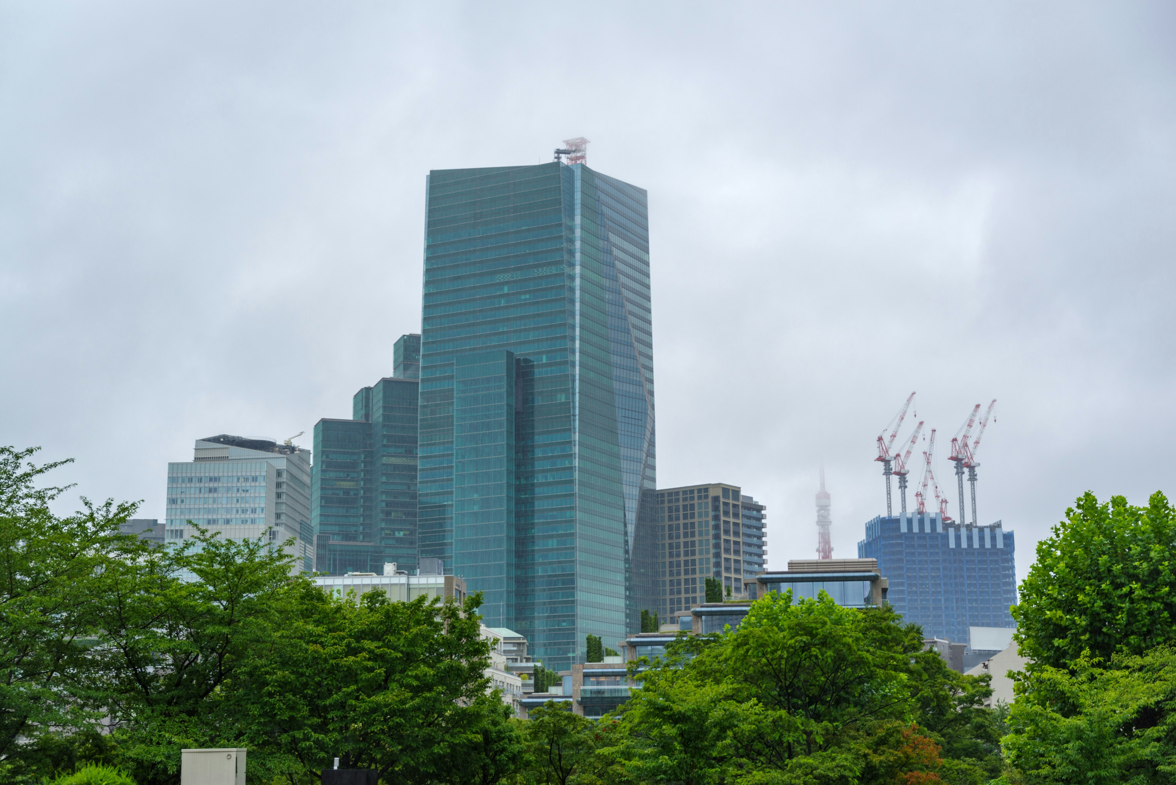 Modern skyscrapers surrounded by greenery under a cloudy sky